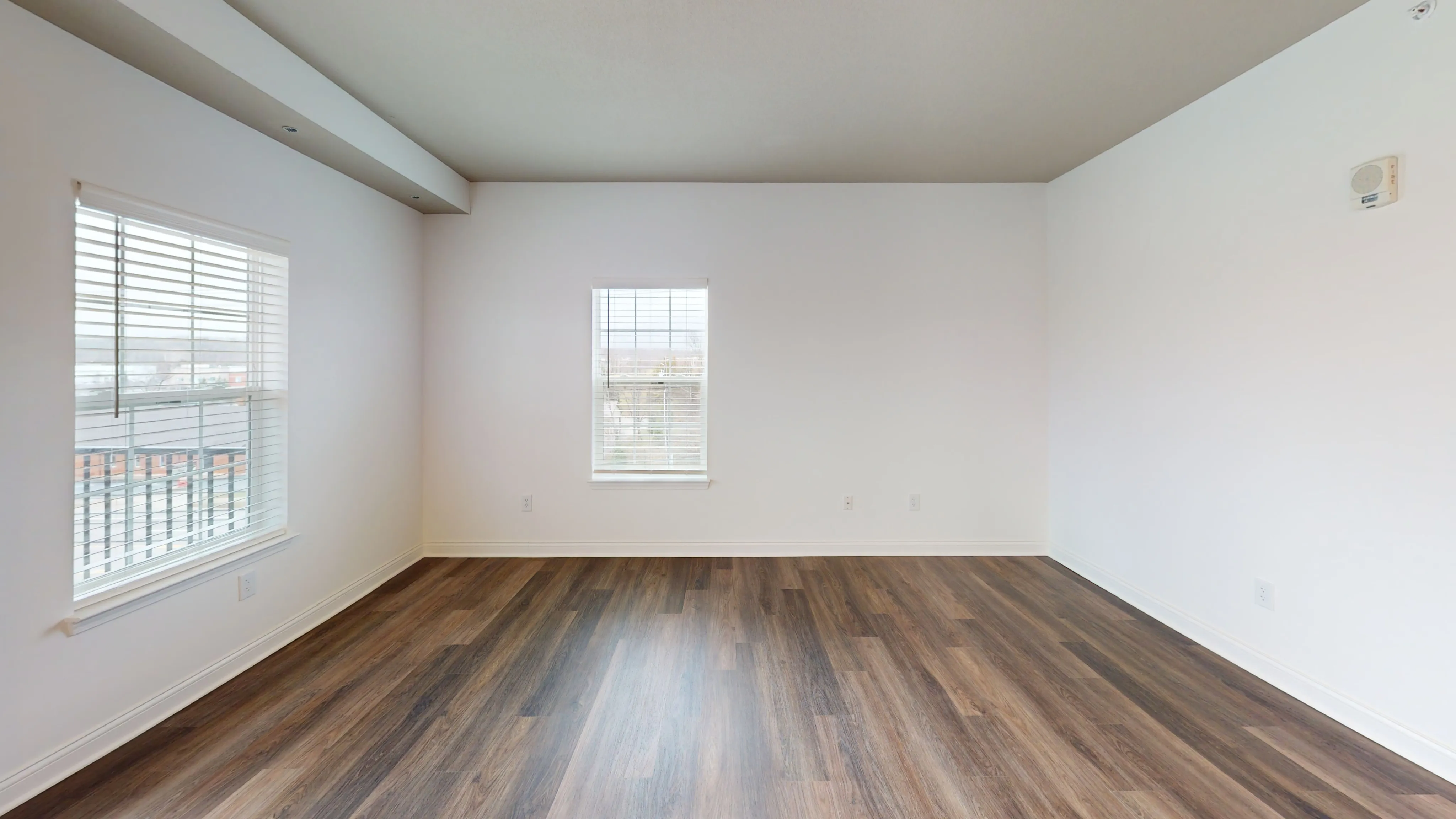 Bright and spacious room with elegant hardwood floors and large windows, perfect for a cozy living area or stylish office.