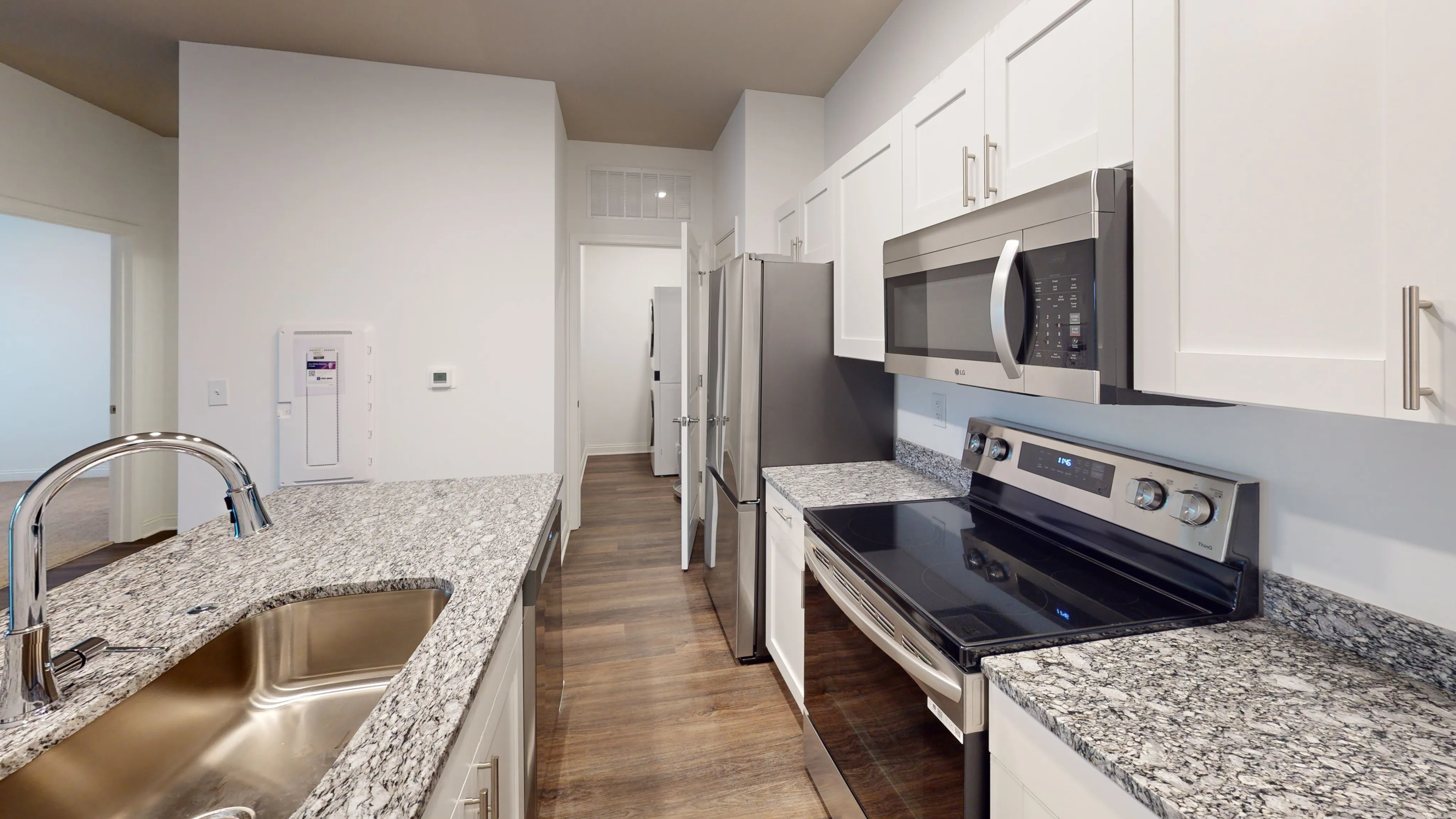 Modern kitchen with sleek granite countertops, stainless steel appliances, and a bright, open layout.