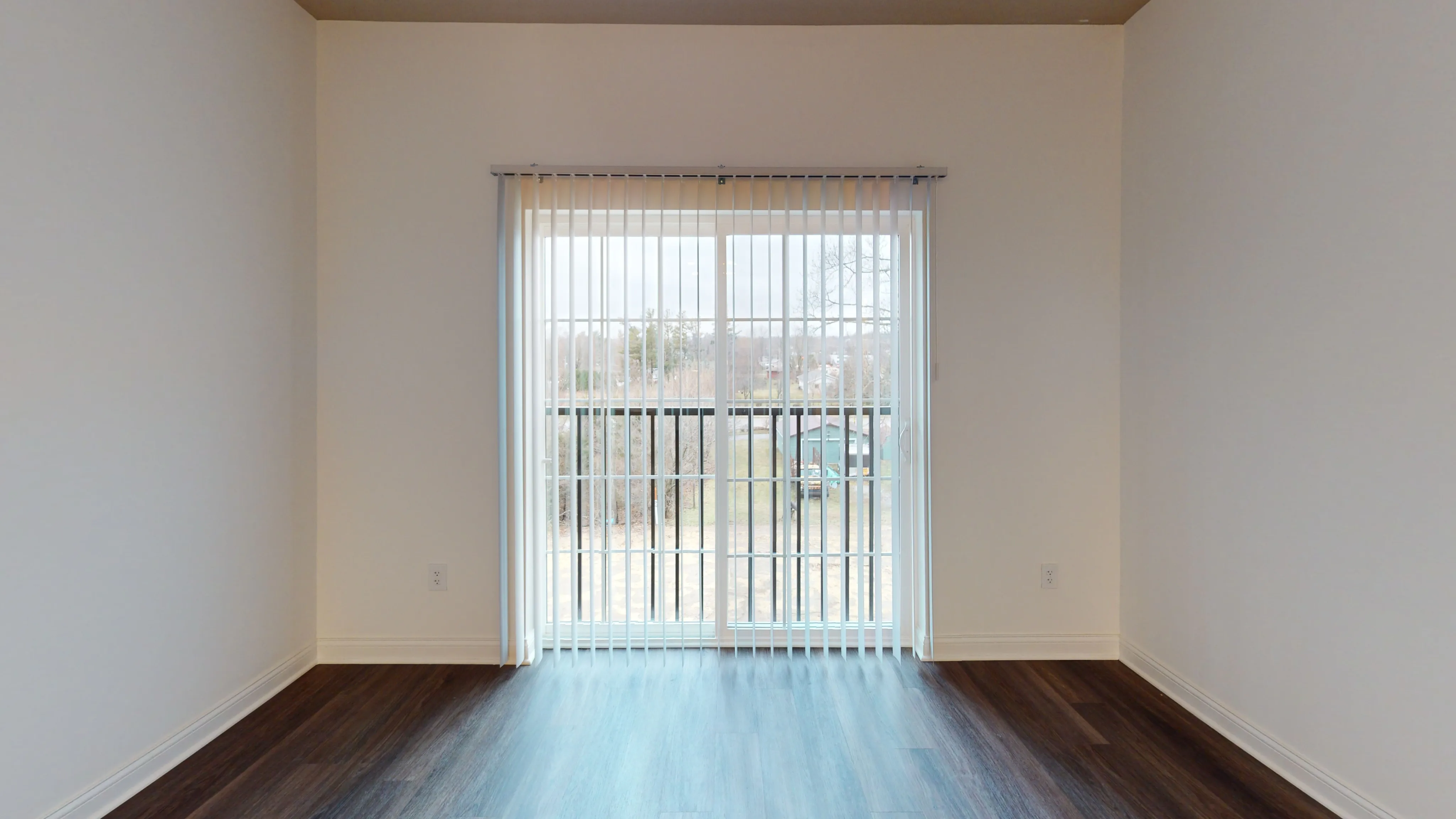 Bright room with floor-to-ceiling window and elegant wooden flooring, offering a serene view of nature.