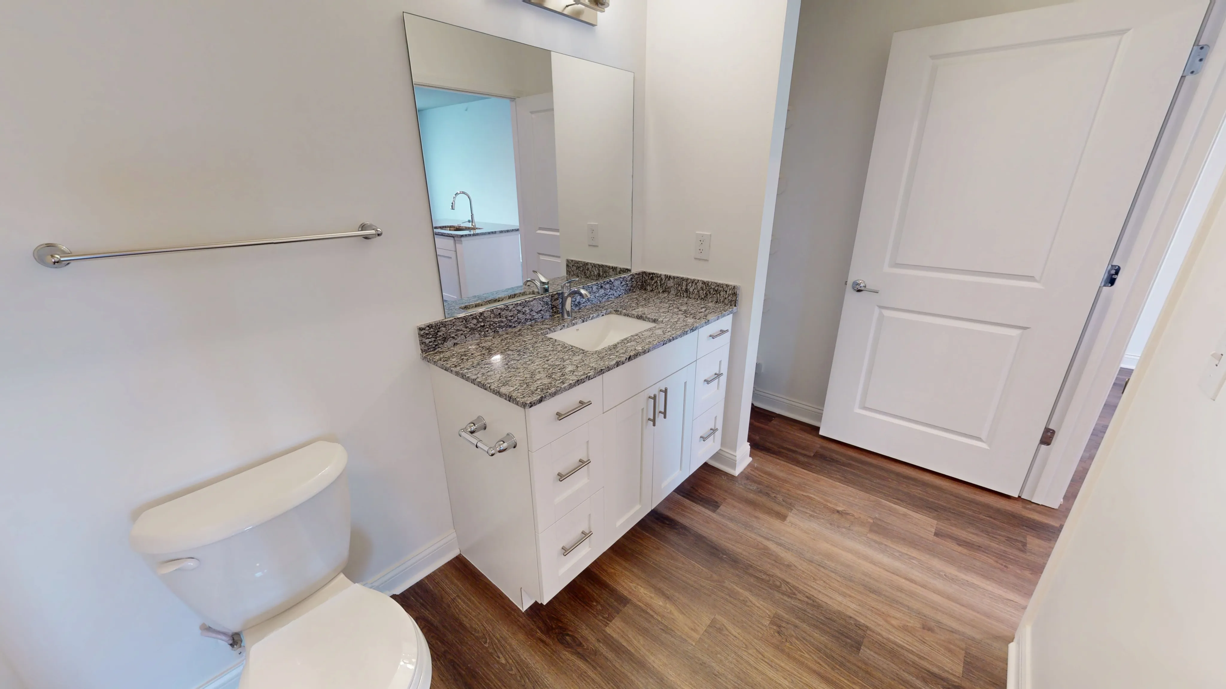 Elegant bathroom featuring a sleek granite countertop, modern fixtures, and rich wood flooring.