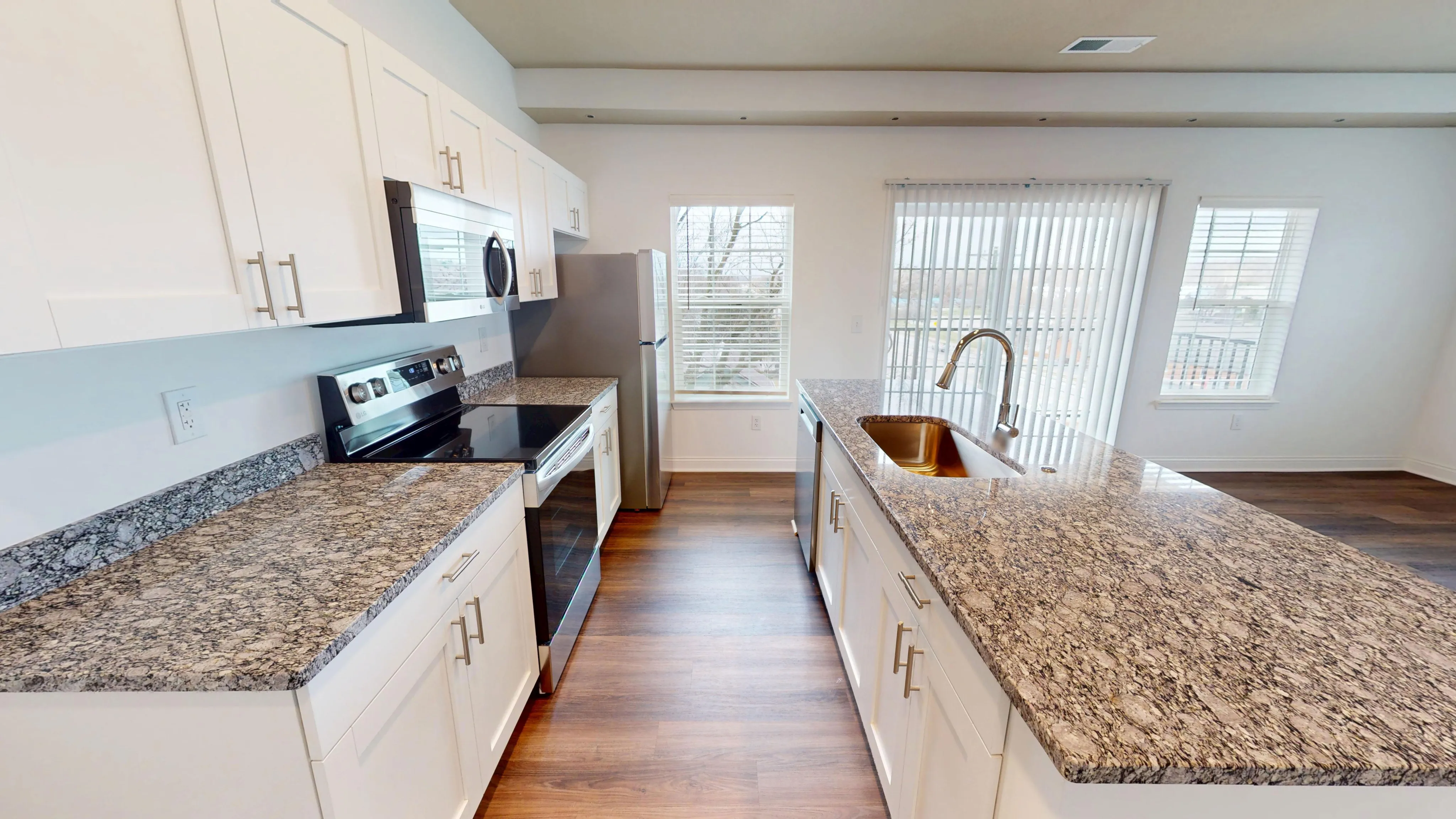 Modern kitchen featuring granite countertops, stainless steel appliances, and bright natural light from large windows.