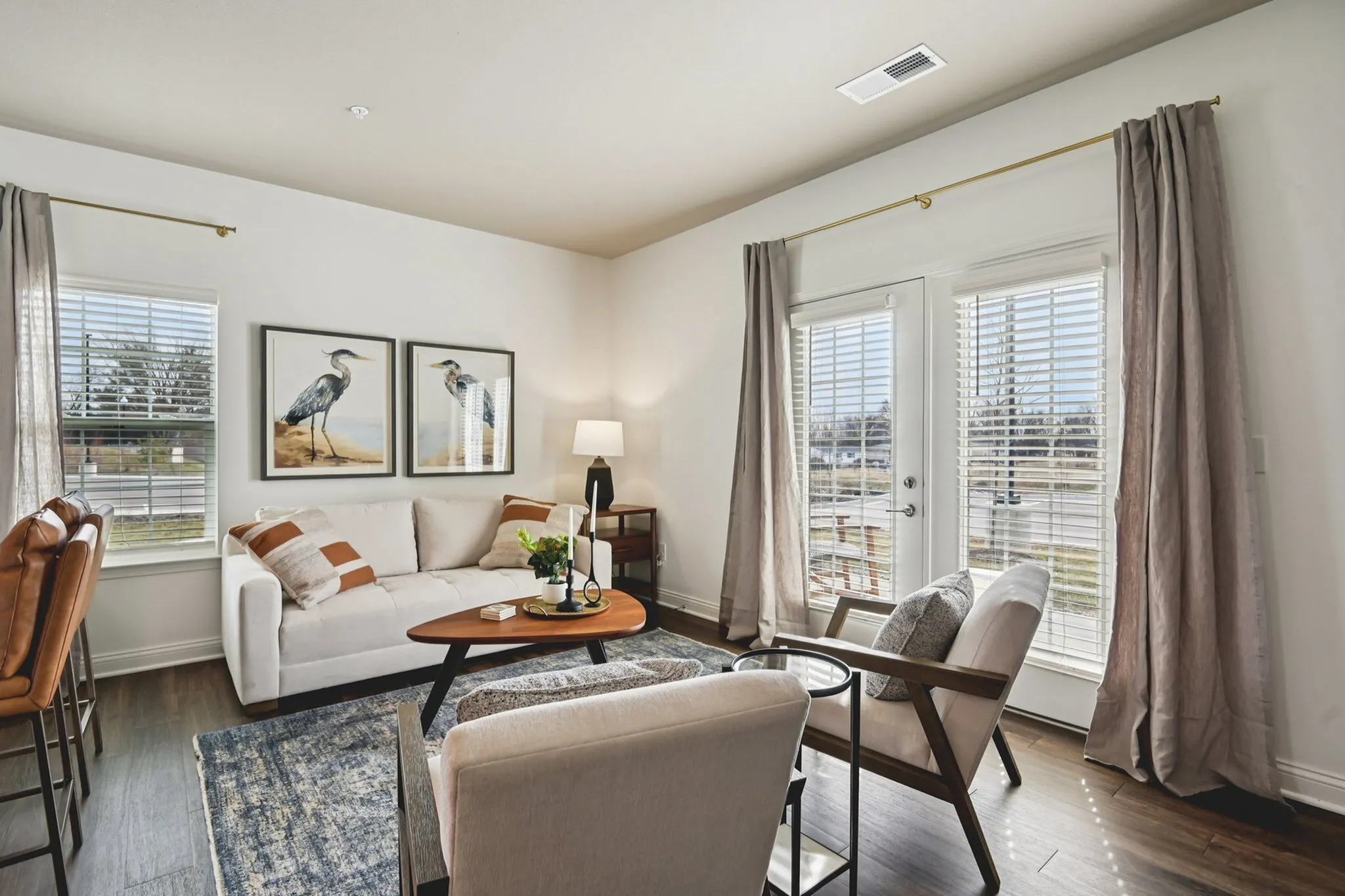Bright, welcoming living room with chic decor, featuring a cozy sofa, stylish armchairs, and large windows with abundant natural light.