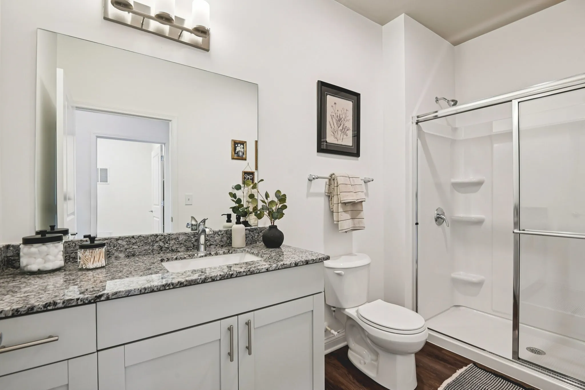 Modern bathroom with a sleek glass shower, elegant granite countertop, and stylish fixtures, offering a serene and inviting atmosphere.