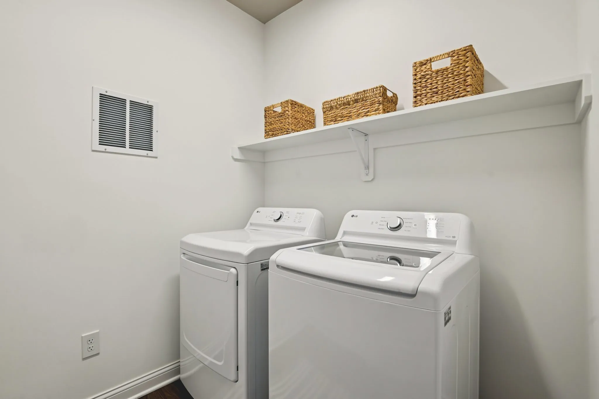 Modern laundry room featuring sleek washer and dryer set, with convenient overhead storage and wicker baskets.