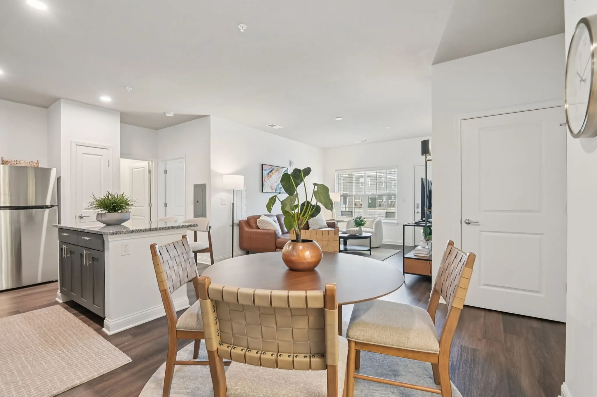 Bright open-concept living and dining area with modern kitchen island, stylish furnishings, and natural light.