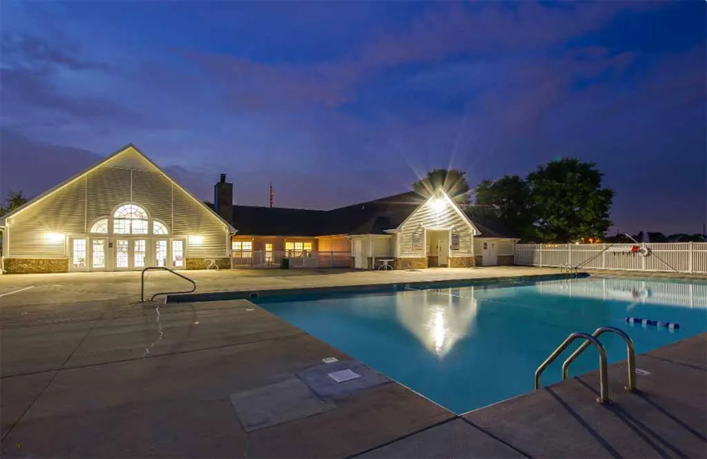 Stunning twilight view of elegant clubhouse and sparkling swimming pool, perfect for evening relaxation and entertainment.