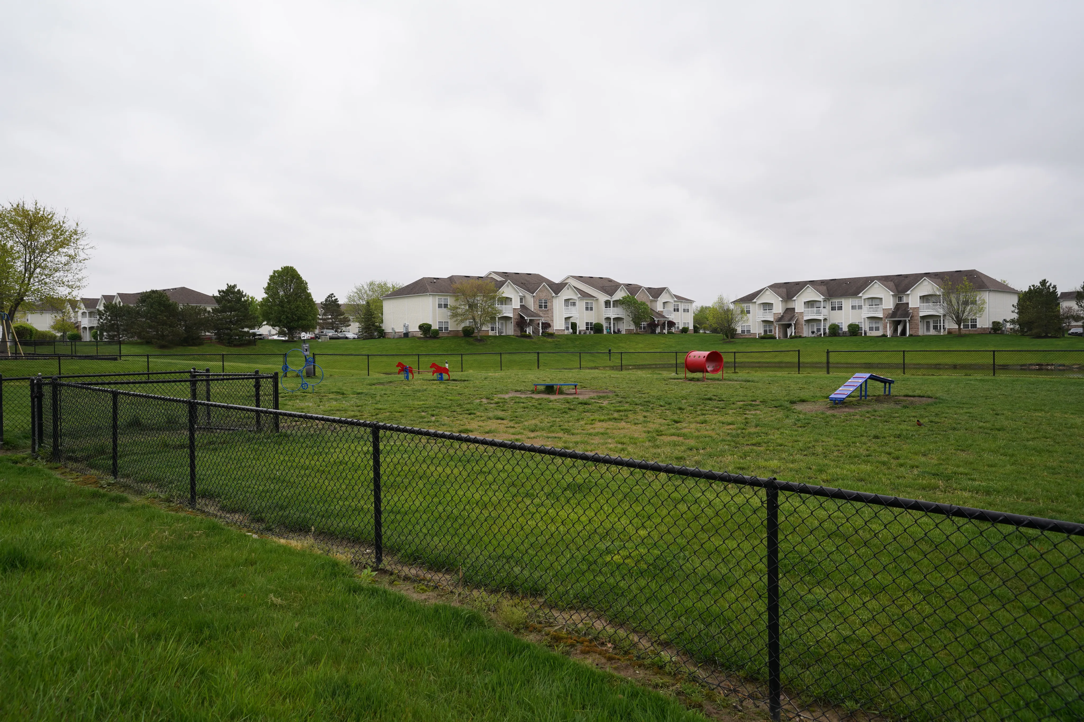 Expansive apartments with lush green surroundings, featuring a spacious fenced playground for outdoor activities.