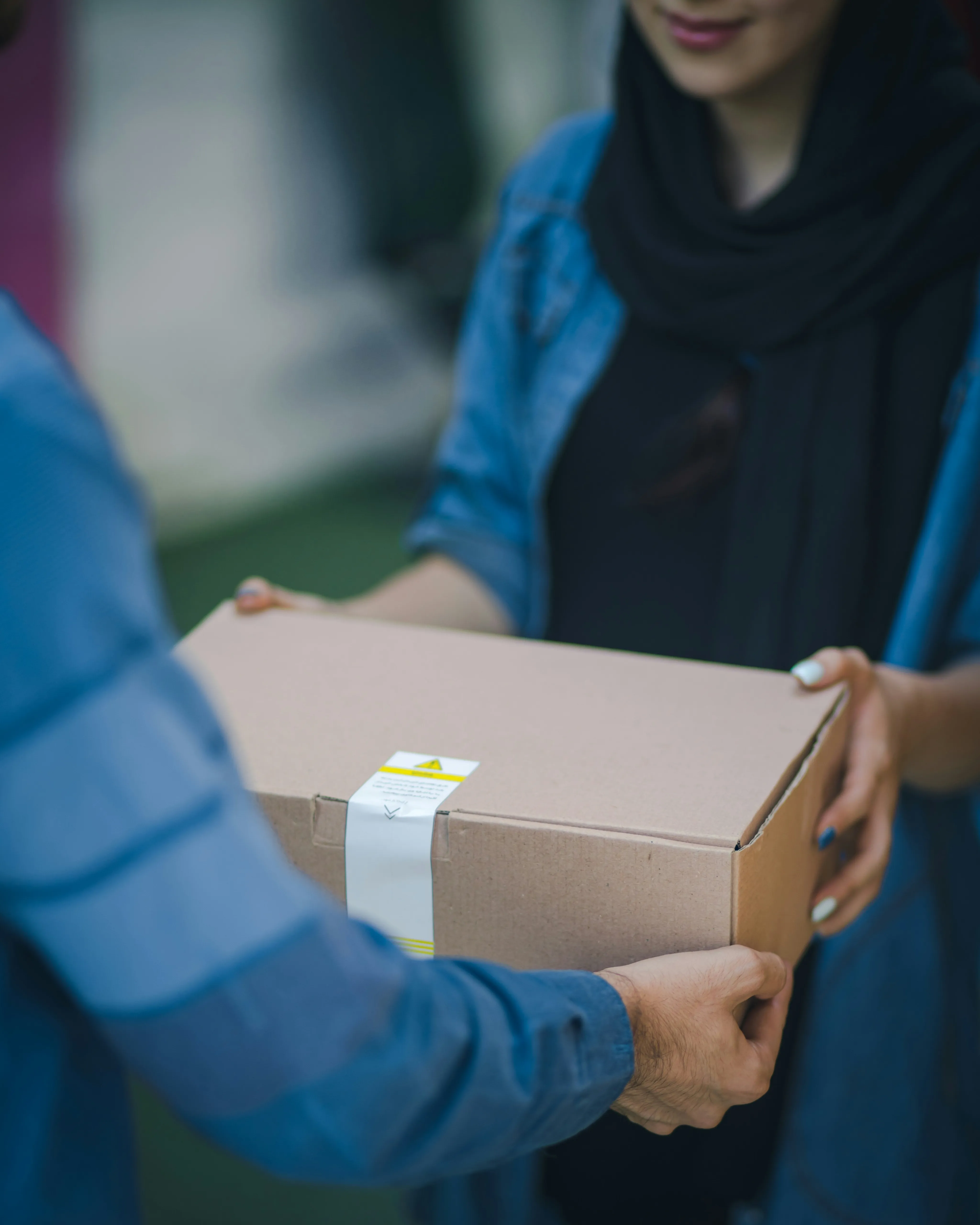 Close-up of hands exchanging a delivery package, highlighting courier service interaction.