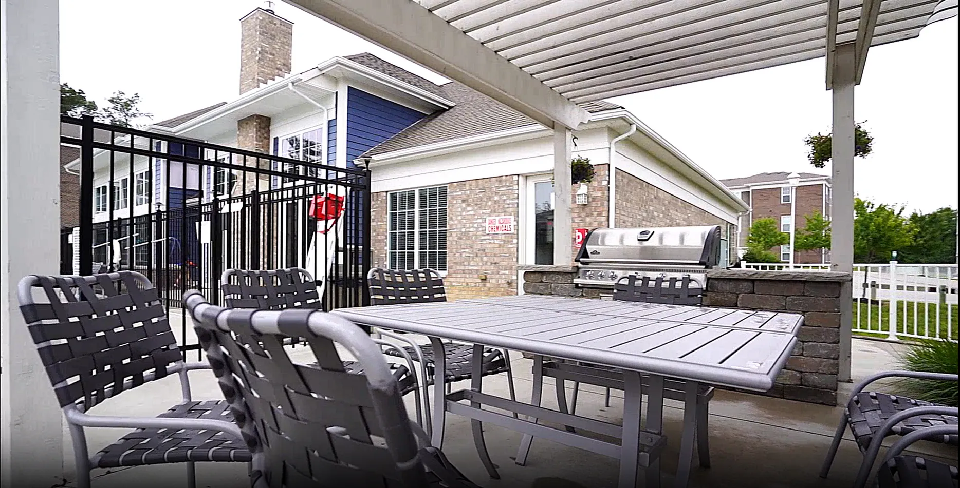 Charming patio area with a modern dining set under a pergola, featuring a sleek grill and cozy seating, perfect for outdoor gatherings.