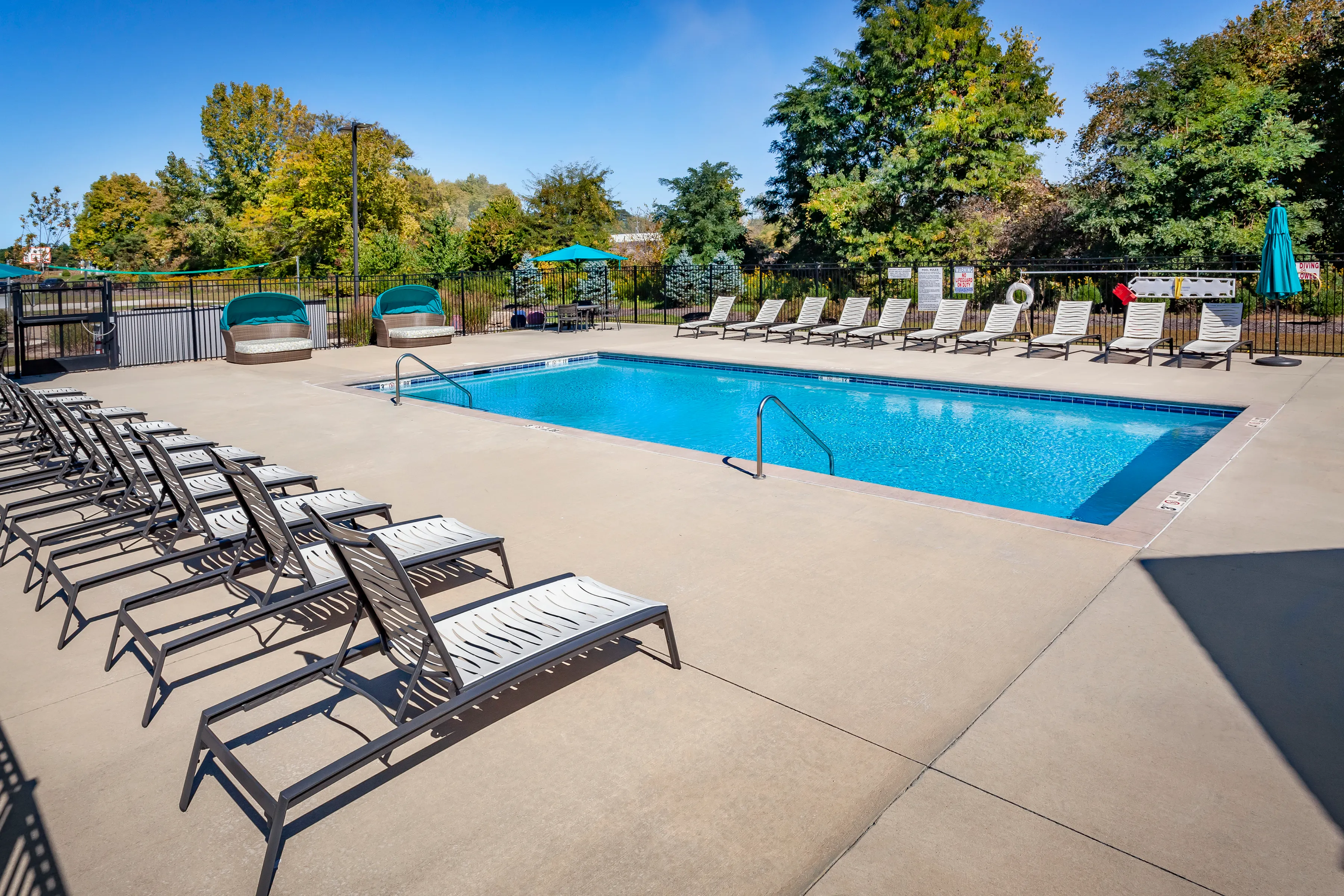 Inviting outdoor pool area with stylish loungers and lush greenery, perfect for relaxation and soaking up the sun.