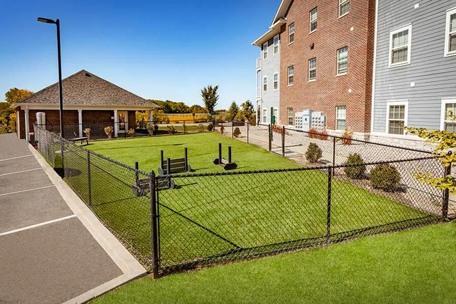 Charming apartment complex with a spacious fenced outdoor area and lush green lawn, perfect for leisure and relaxation.