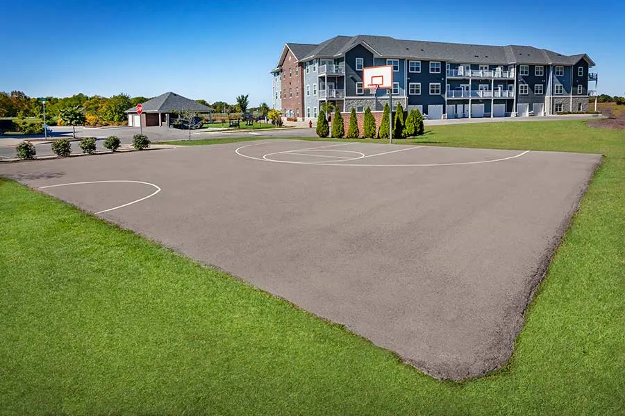 Chic apartment complex with modern balconies overlooking a well-maintained basketball court and lush green surroundings.