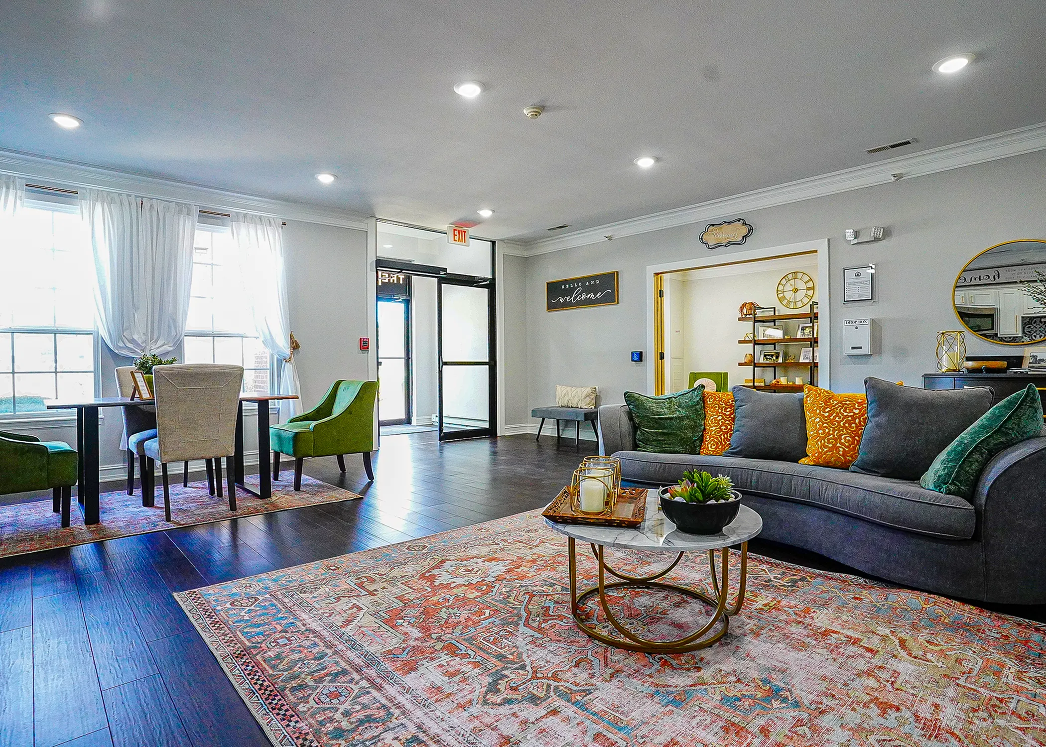 Inviting and spacious living space featuring elegant decor with a cozy gray sofa, vibrant cushions, and a charming coffee table centerpiece. Natural light floods through large windows enhancing the sophisticated ambiance and showcasing stylish hardwood floors.