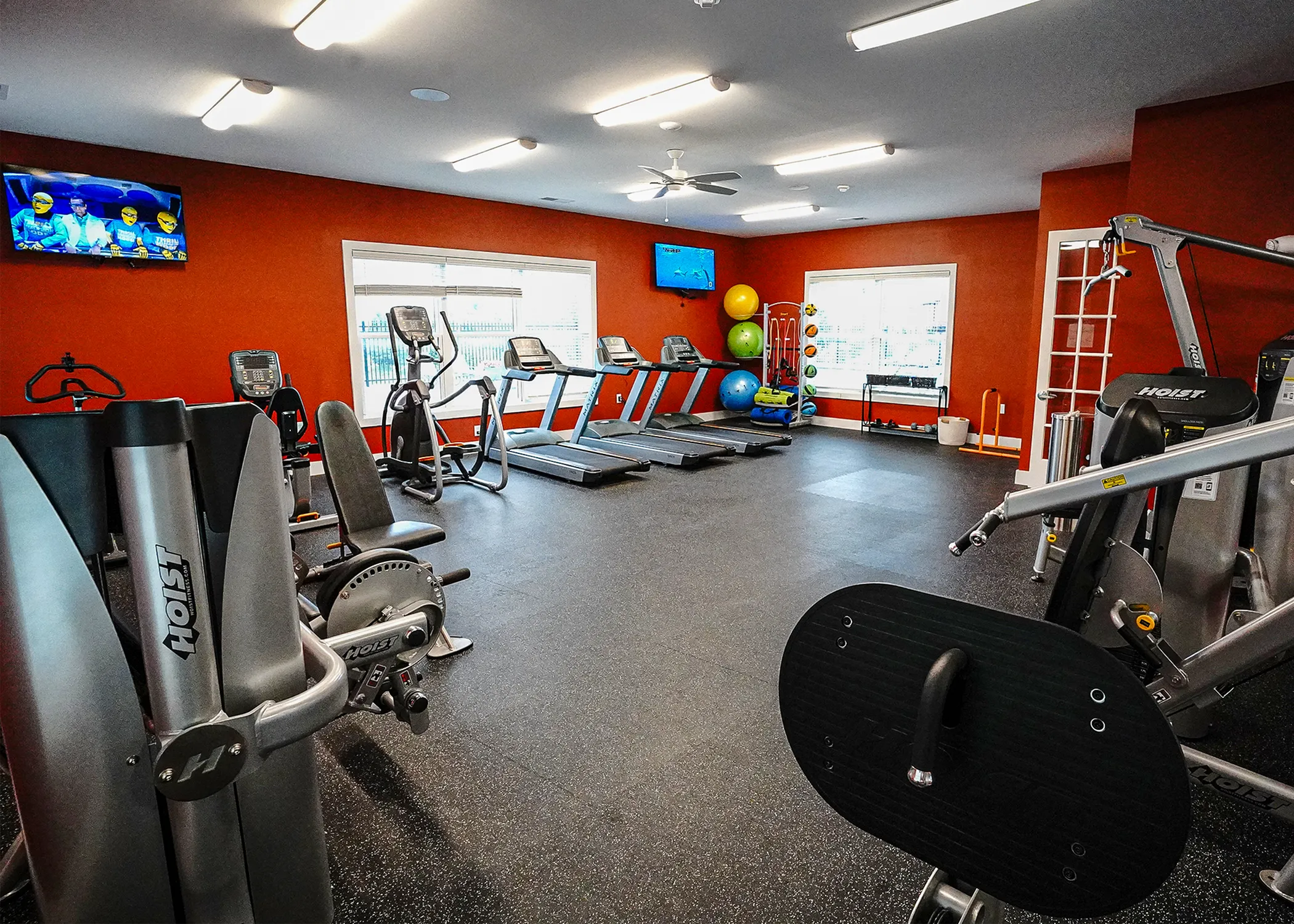 Modern fitness center with state-of-the-art equipment, vibrant orange walls, and ample lighting, perfect for an energizing workout.