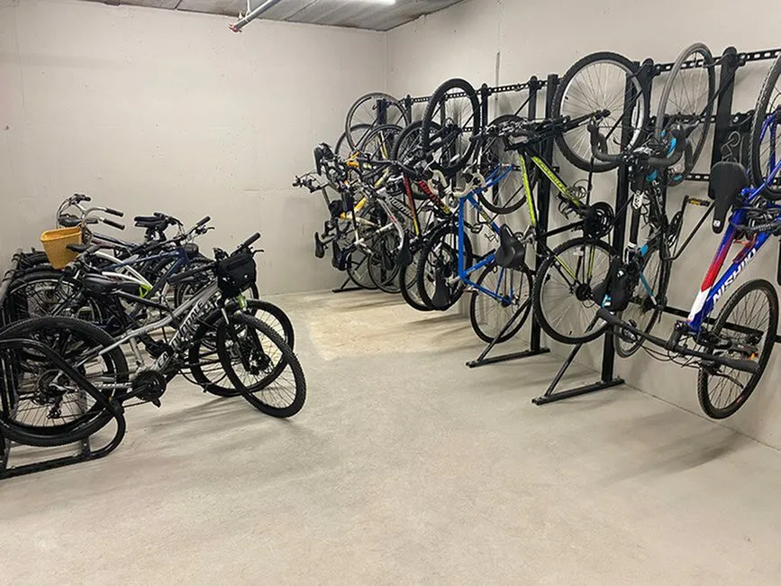 Spacious and secure bike storage room featuring wall-mounted racks with various bicycles neatly organized.