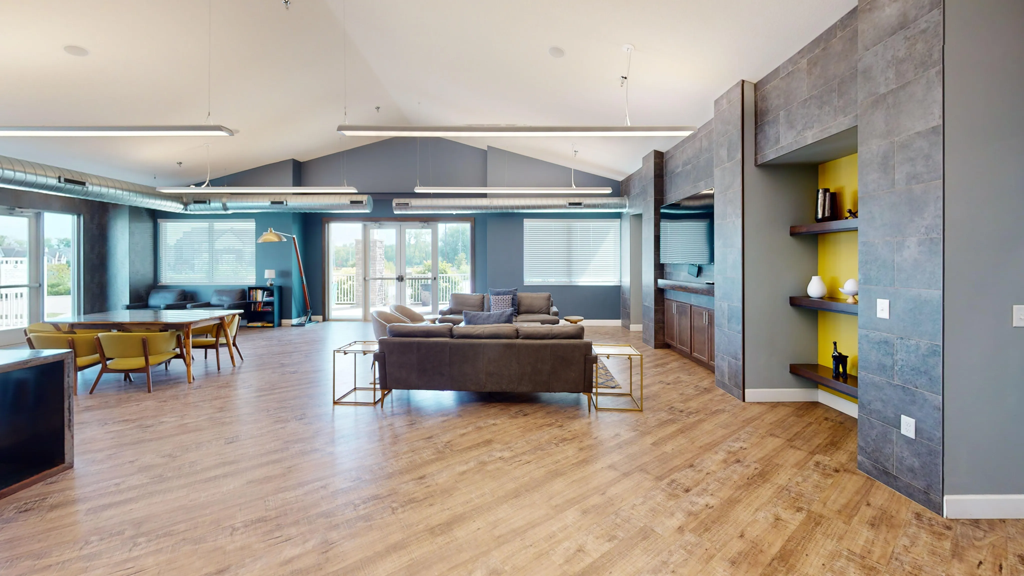 Spacious living area with modern decor, featuring sleek wooden floors, cozy seating, and abundant natural light from large windows.
