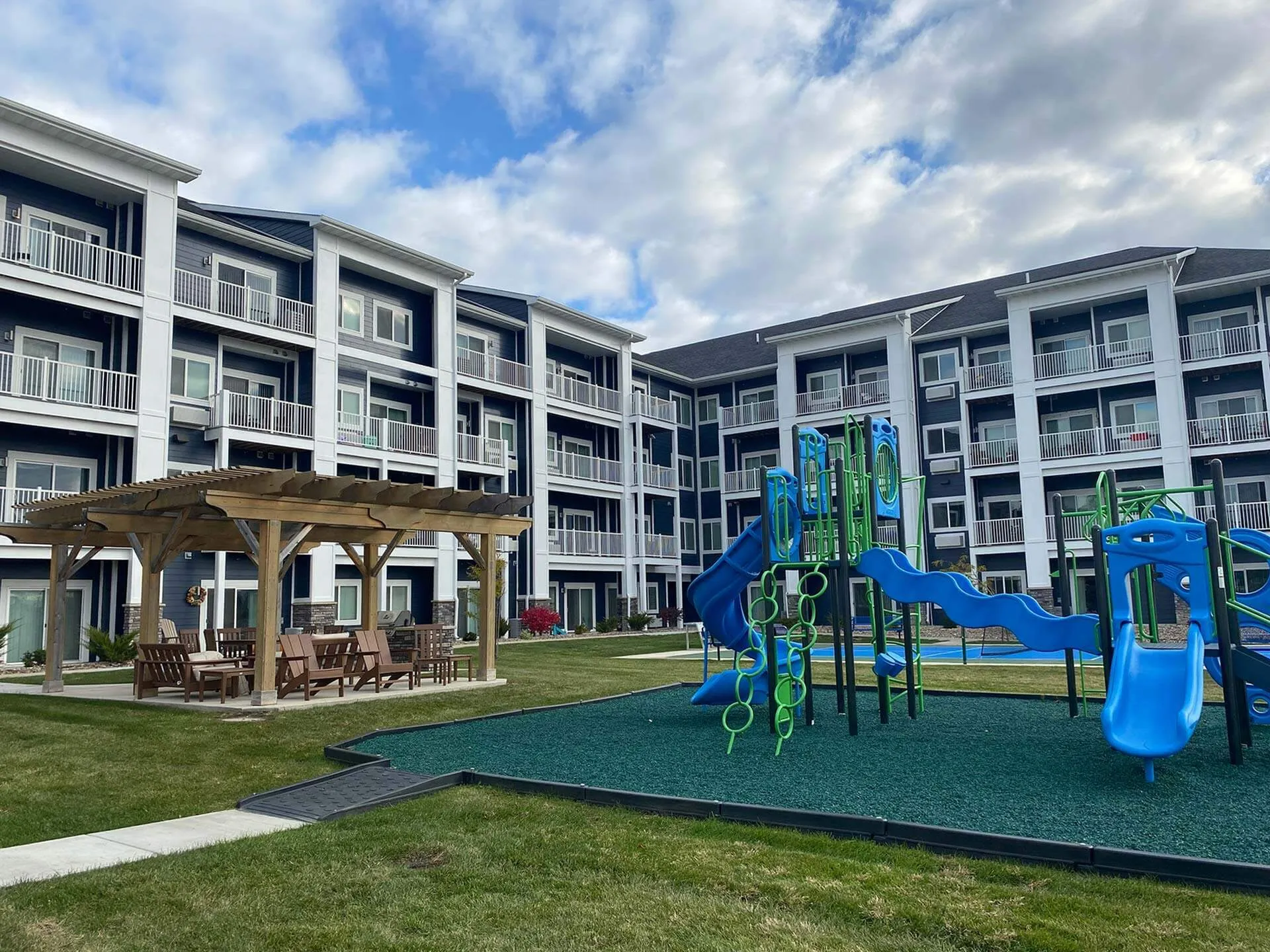 Charming apartment complex featuring elegant balconies, a vibrant playground, and a cozy outdoor patio area, perfect for family living.