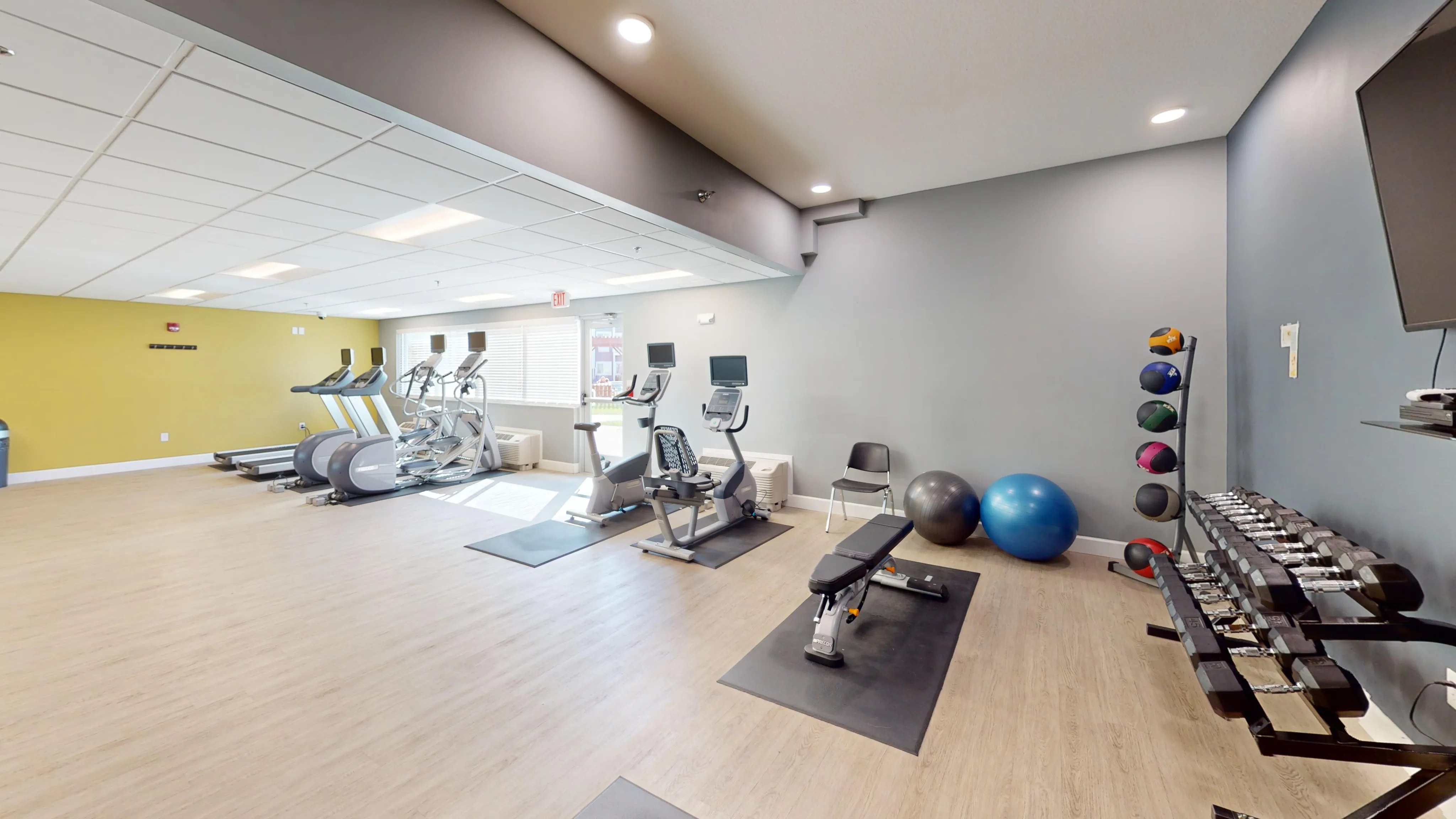 Bright and modern fitness center with state-of-the-art equipment, featuring treadmills, exercise bikes, free weights, and yoga balls.