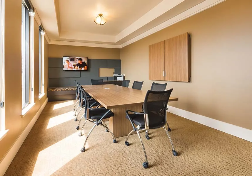 Elegant meeting room with large windows, stylish wooden table, and modern chairs, ideal for productive business discussions.