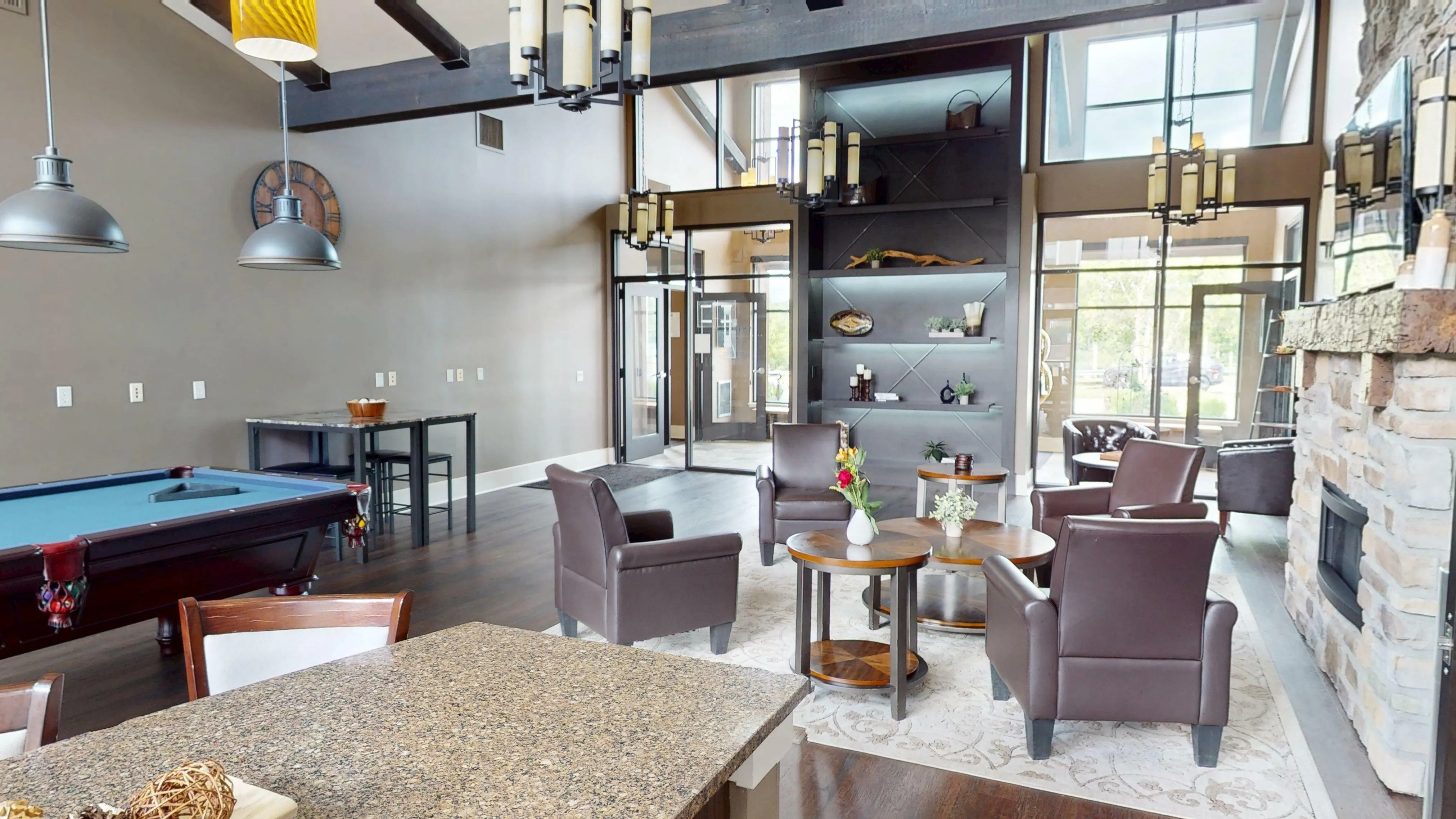 Chic open-concept living area with elegant leather chairs, modern lighting, and a stylish stone fireplace, perfect for entertaining.