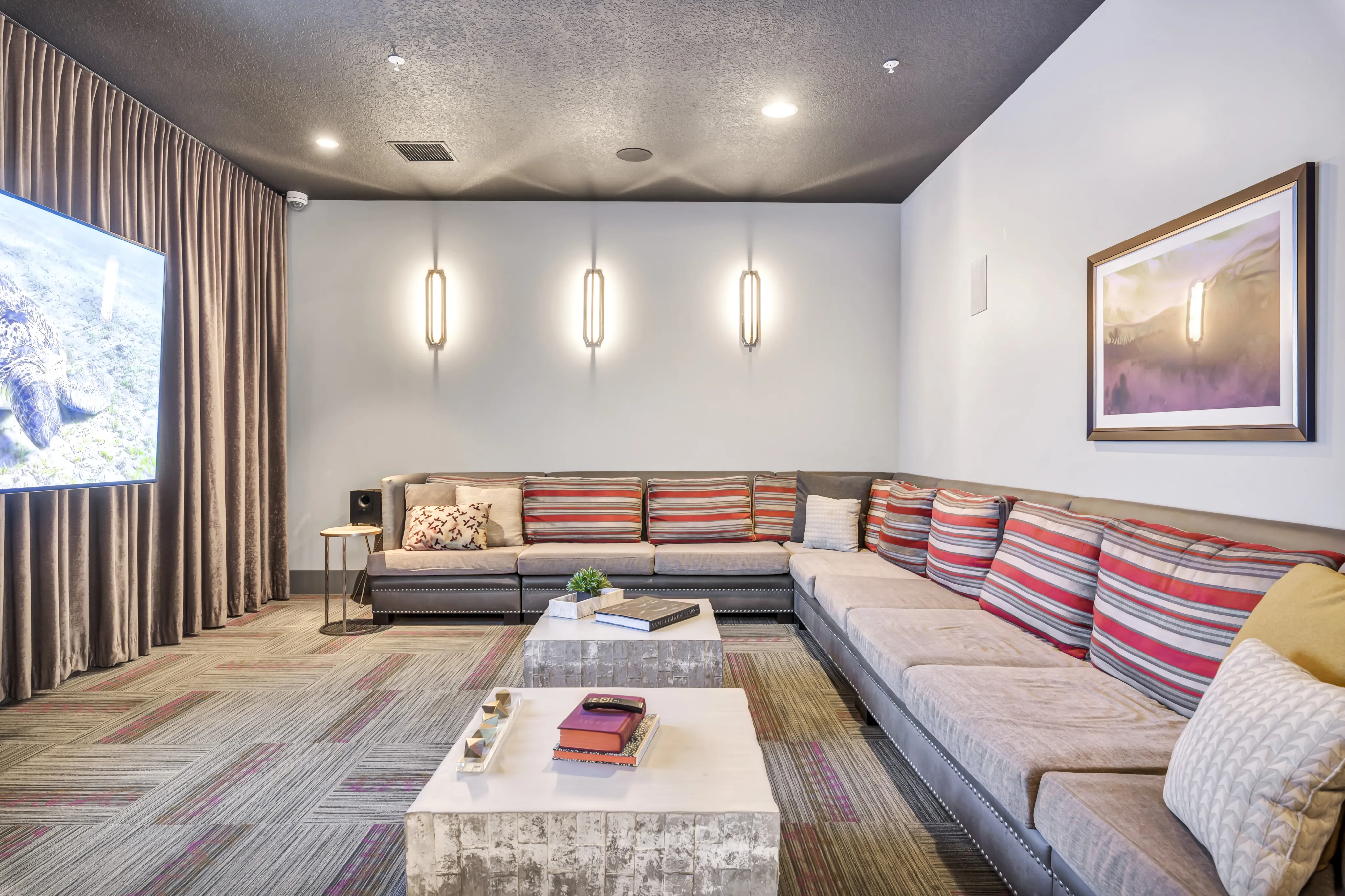 Elegant entertainment room with a cozy L-shaped sofa, vibrant striped cushions, ambient lighting, and a large TV screen, designed for ultimate relaxation.