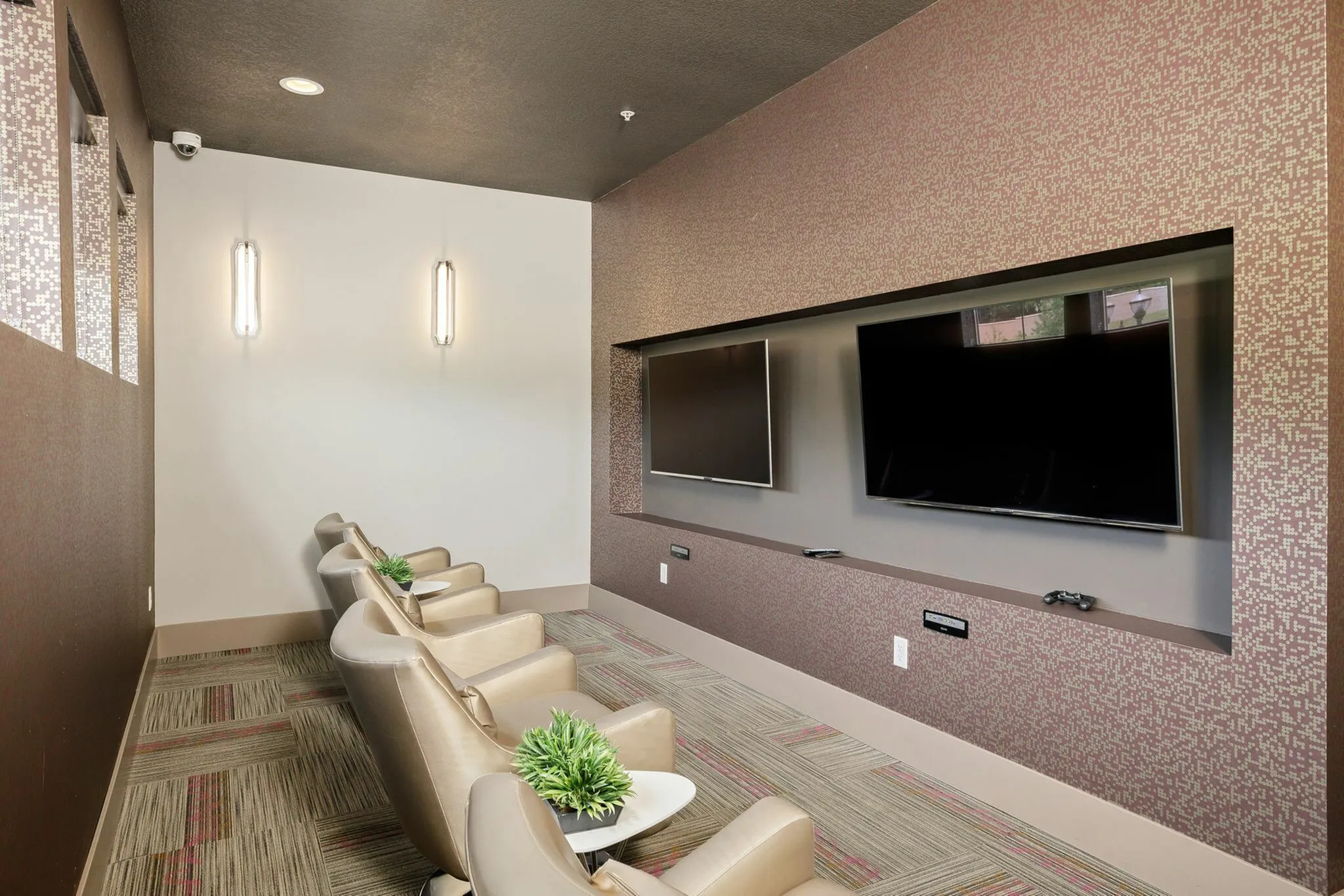 Modern entertainment room featuring sleek leather seating, dual flat-screen TVs, and ambient lighting for a luxurious viewing experience.
