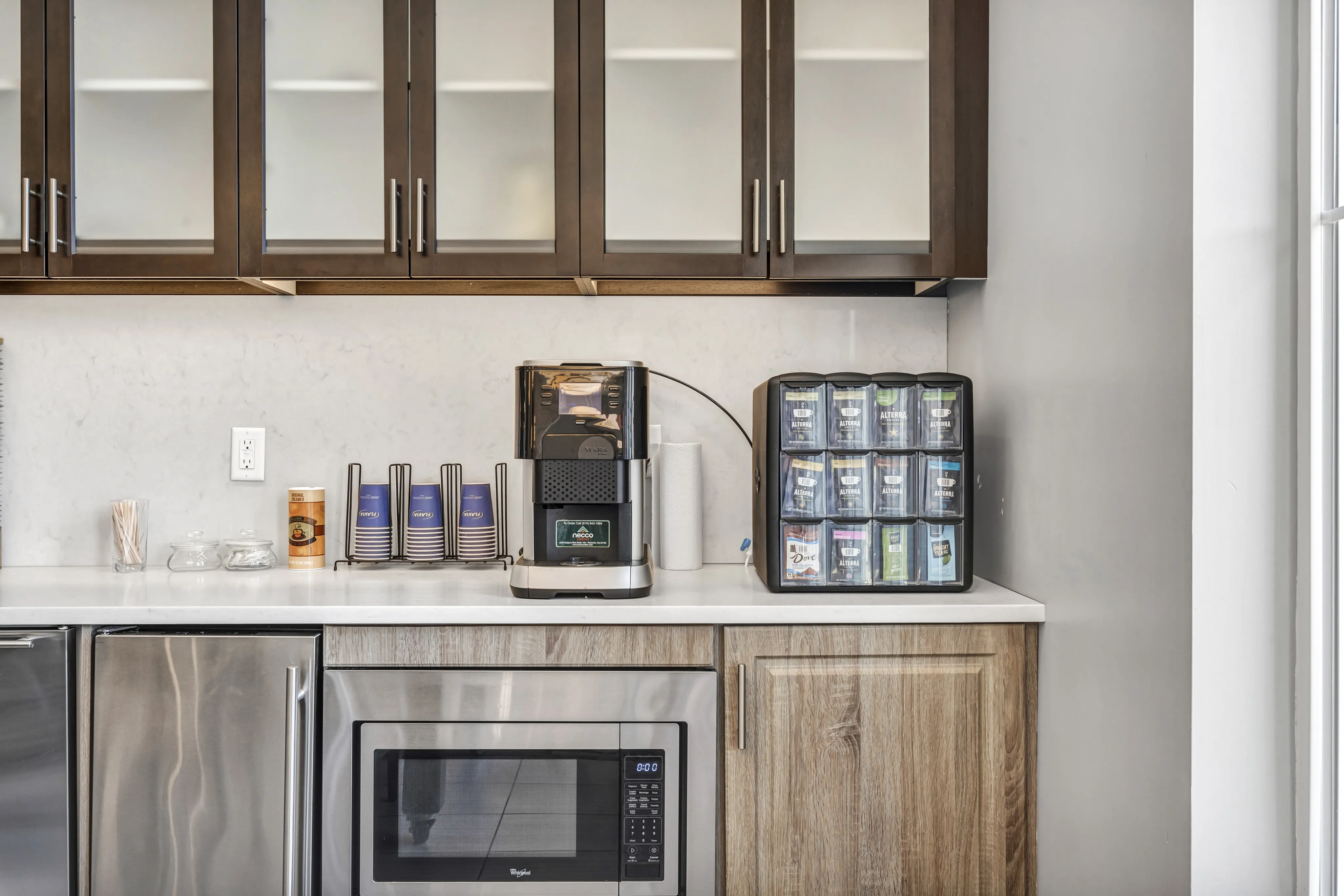 Modern kitchenette with sleek cabinetry, convenient coffee station, and under-counter microwave for a stylish and functional space.