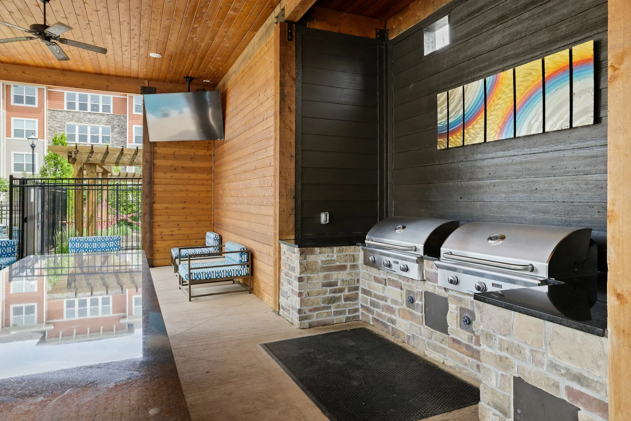 Chic outdoor lounge featuring dual stainless steel grills, stylish seating, and vibrant art, perfect for entertaining.