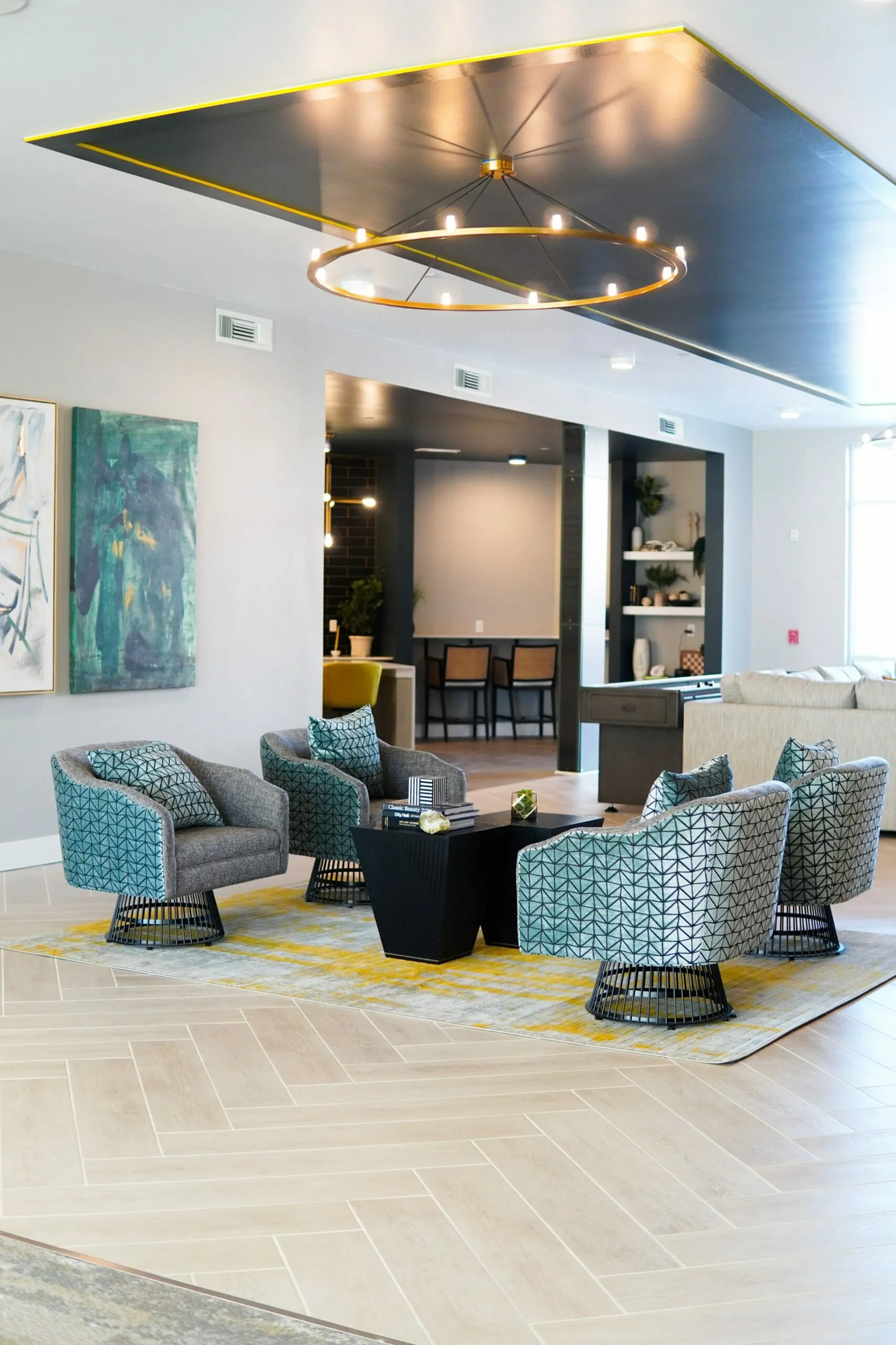Sophisticated living room featuring chic patterned chairs, a sleek coffee table, modern artwork, and elegant lighting in an open-concept space.