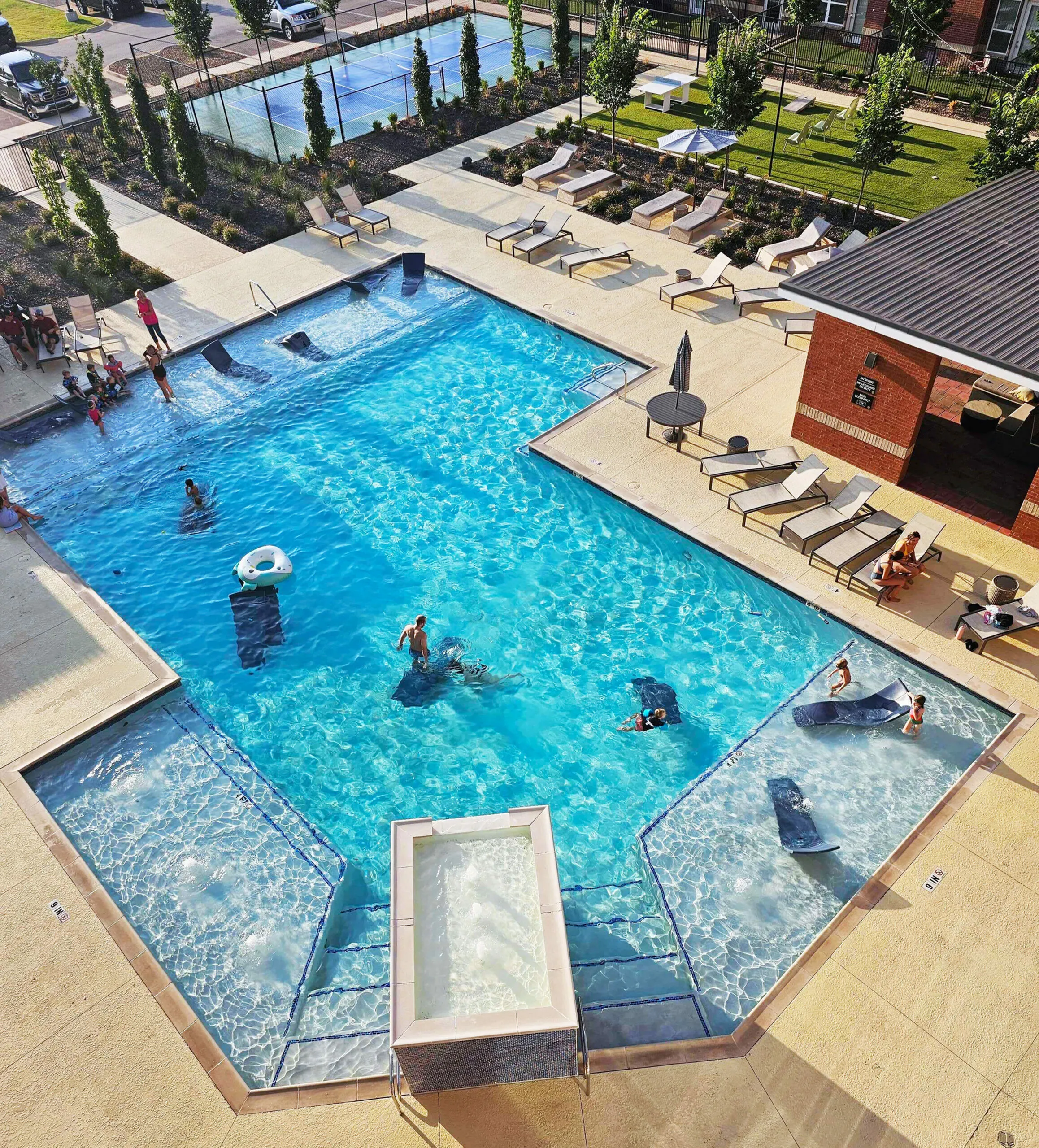Inviting outdoor pool area with sun loungers, modern design, and landscaped surroundings for a relaxing community experience.