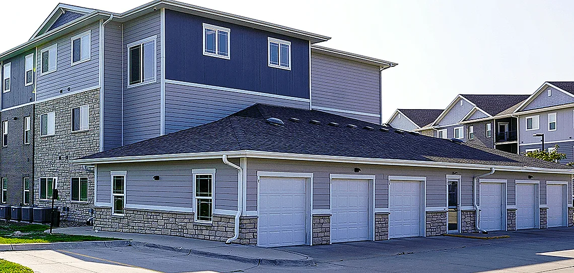 Modern apartment complex with spacious garages and vibrant green surroundings, offering a serene and comfortable living environment.