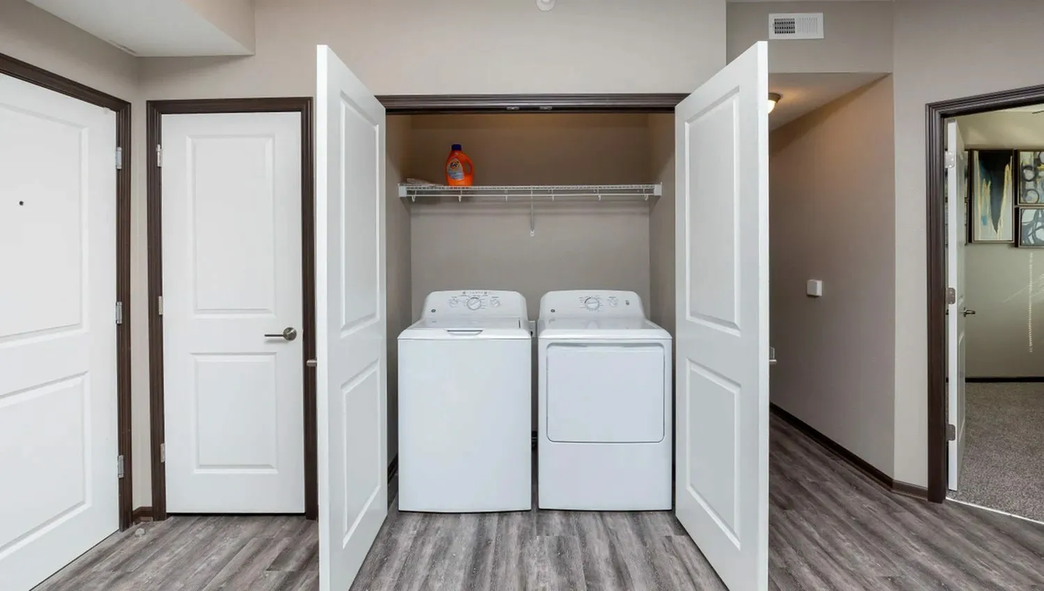 Sleek apartment laundry nook with modern washer and dryer, elegant doors, and stylish flooring.