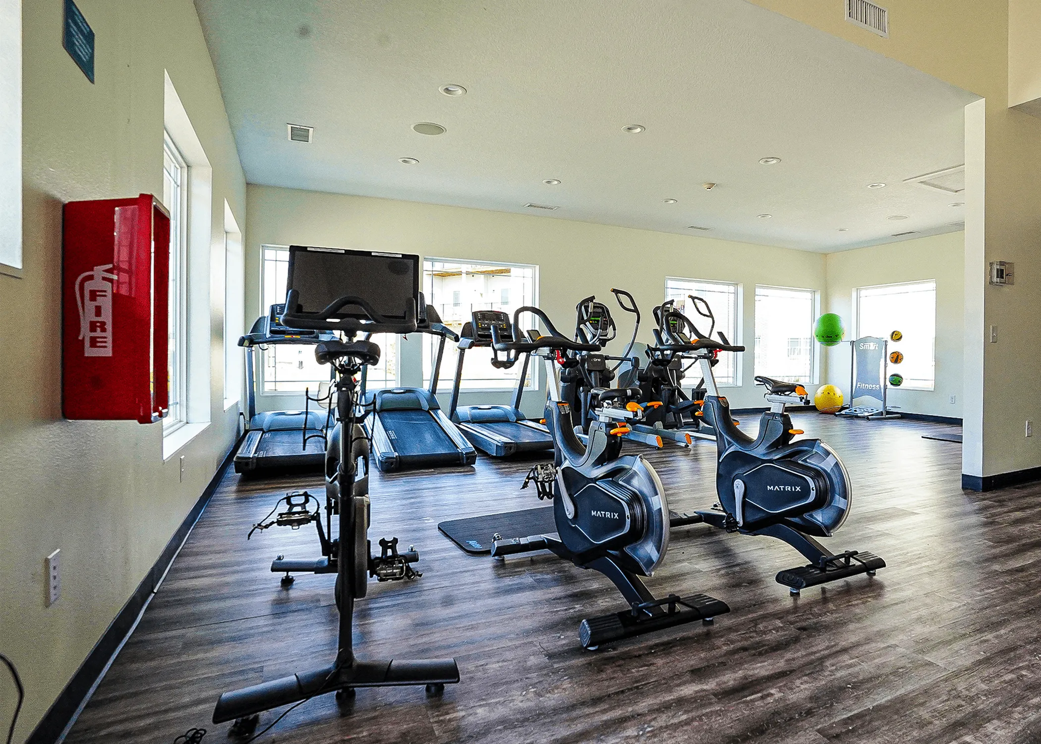 Bright and modern fitness center equipped with state-of-the-art exercise bikes and treadmills, featuring large windows for natural light.
