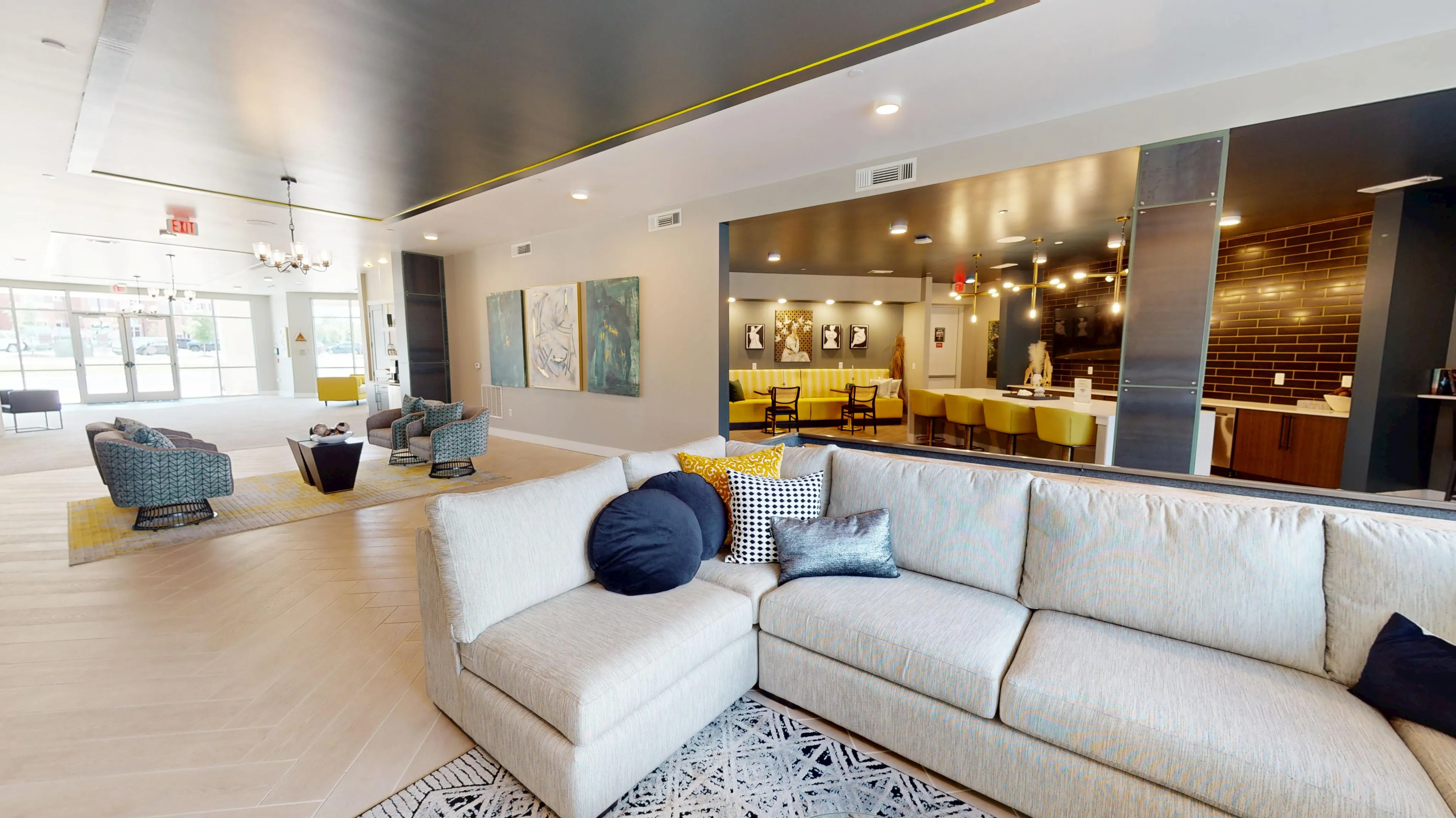 Luxurious open-plan living space with a modern sectional sofa, vibrant yellow accents, and stylish seating area. Features a chic dining section with backlit art and a sleek, contemporary kitchen with minimalist design.