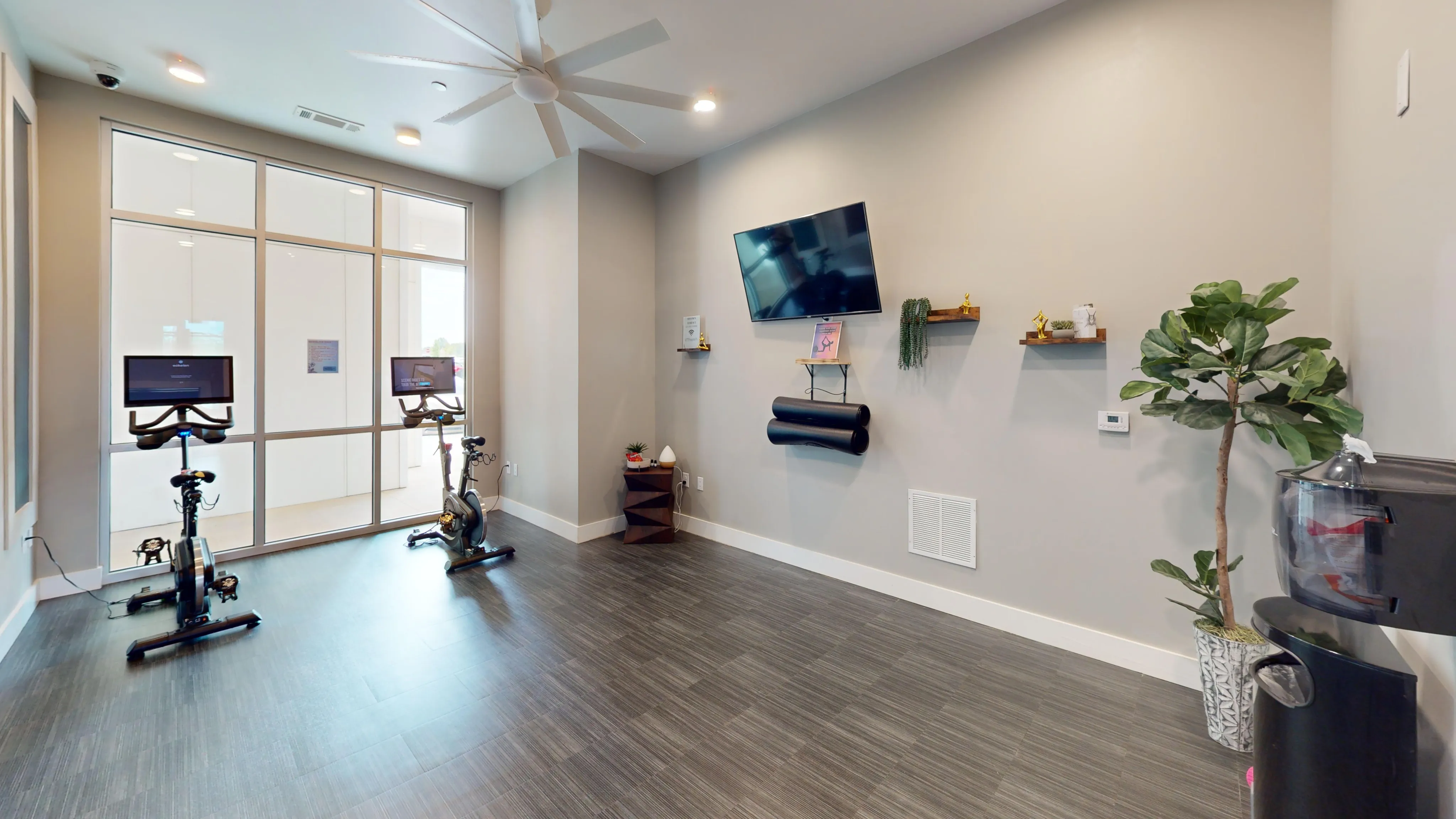 Modern fitness room equipped with two stationary bikes, flat-screen TV, and contemporary decor, perfect for an energizing workout.