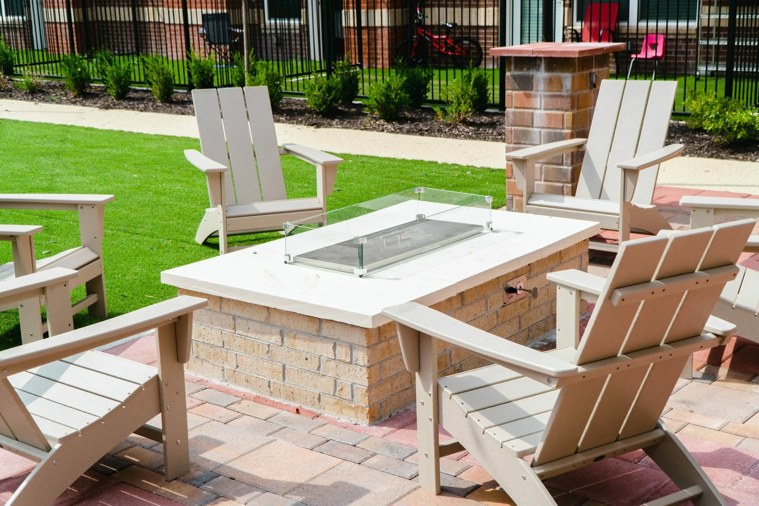 Inviting outdoor patio with stylish wooden chairs encircling a modern fire pit, perfect for relaxing and entertaining.