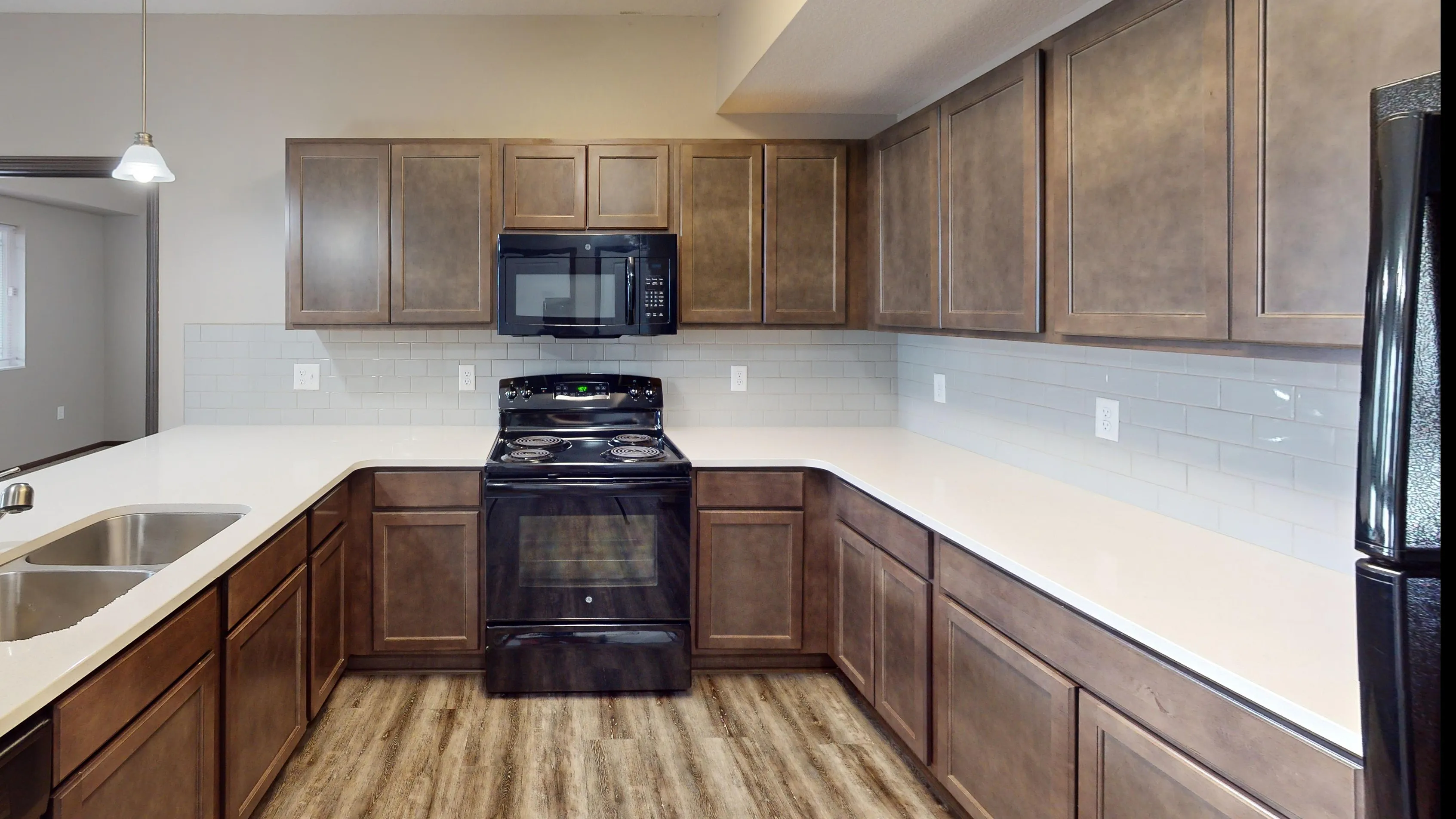 Modern kitchen with sleek wooden cabinets, elegant white countertops, and a black oven, offering a spacious and inviting cooking area.
