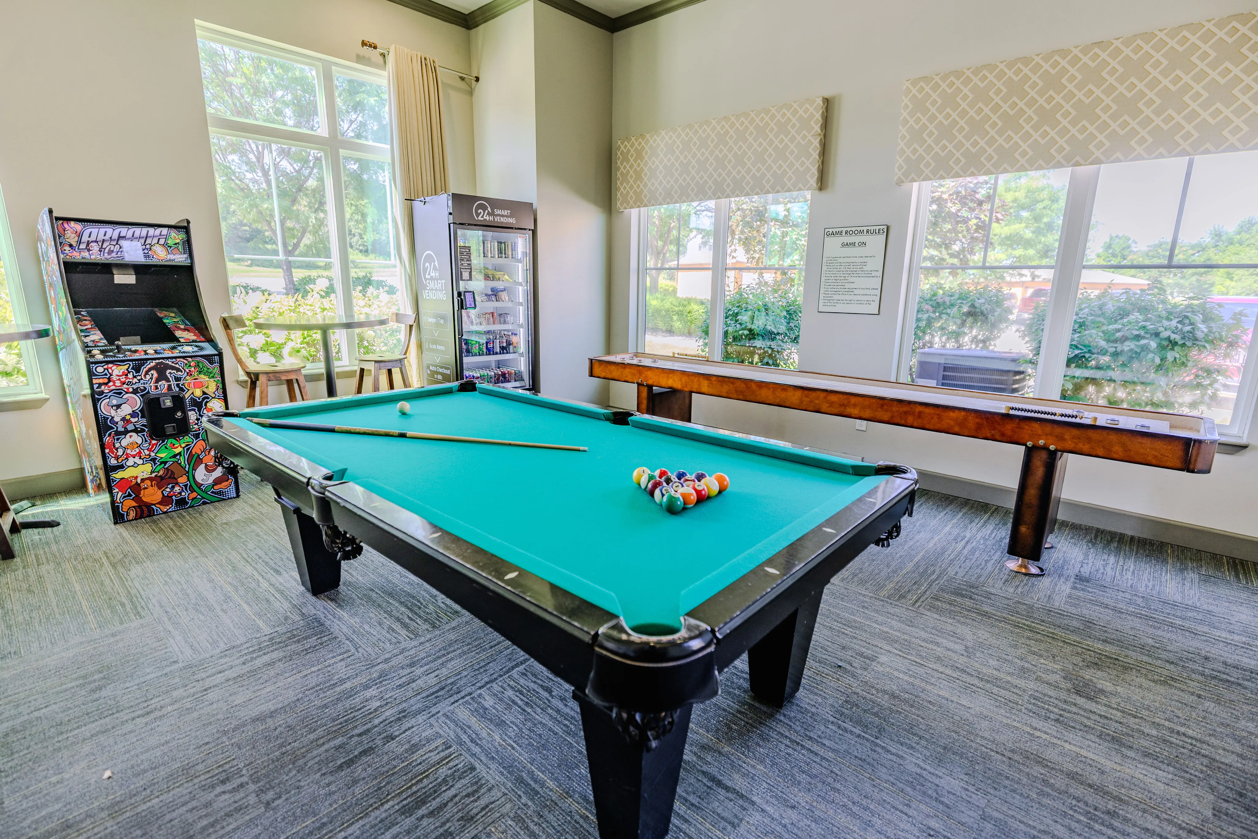 Bright and inviting game room featuring a vibrant pool table, arcade machine, and shuffleboard, perfect for entertainment and relaxation.