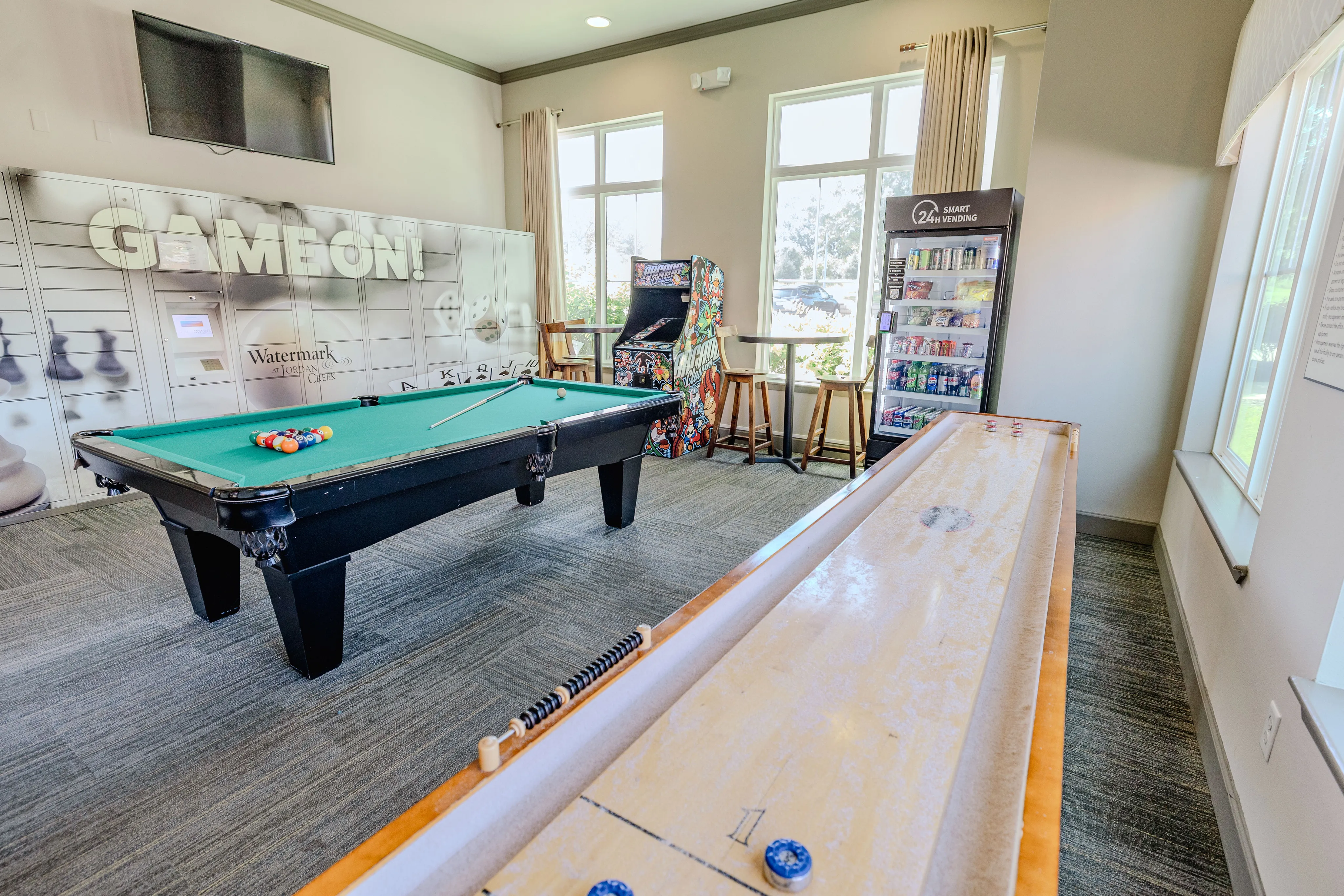 Vibrant entertainment room with a sleek pool table, arcade game, and vending machine, perfect for social gatherings and leisure.