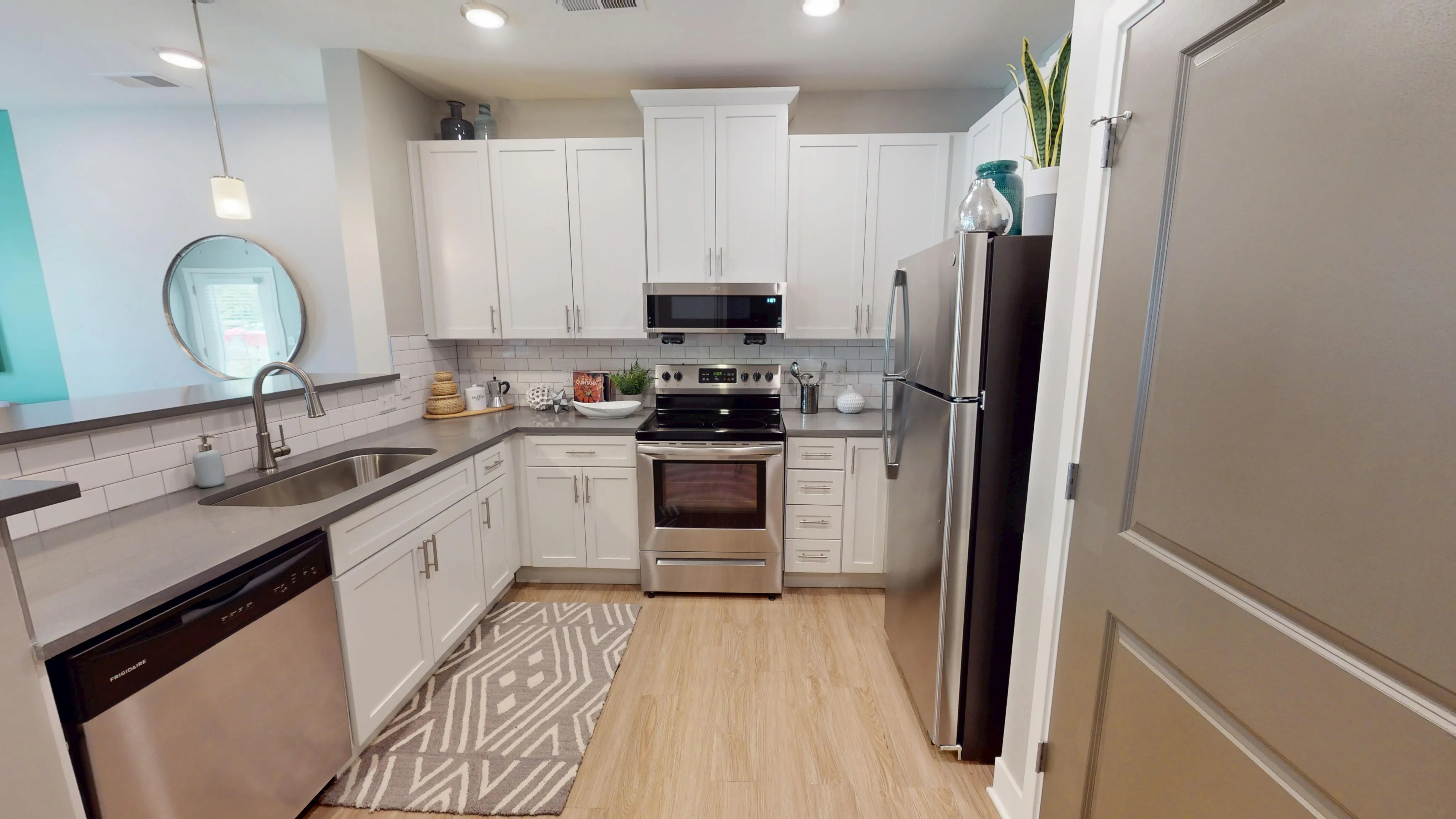 Modern kitchen with sleek stainless steel appliances, elegant white cabinetry, and a stylish backsplash, perfect for culinary inspiration.