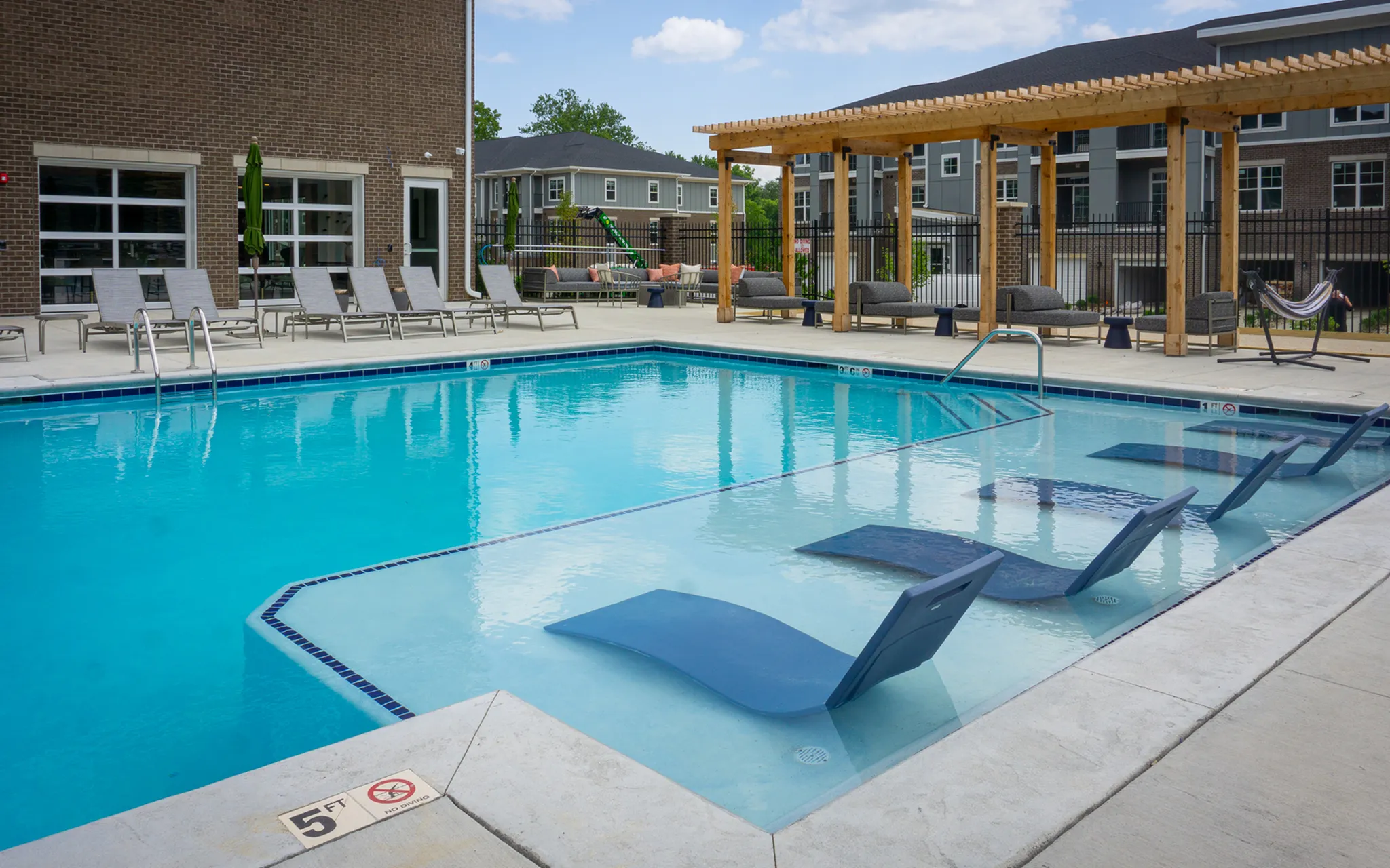 Inviting apartment community pool area with modern lounge chairs, chic pergola, and hammock for ultimate relaxation.