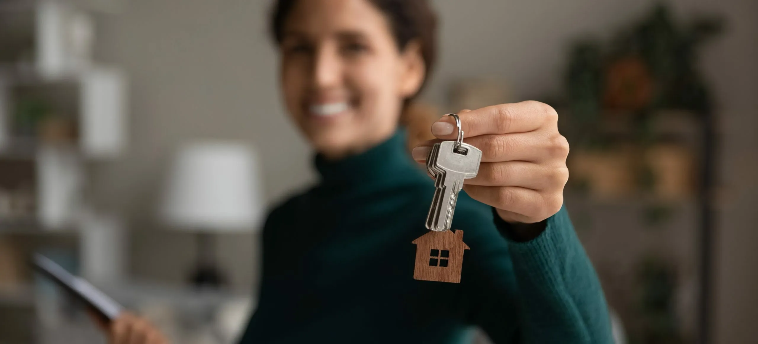 Joyful woman holding new home keys, symbolizing a fresh start and exciting homeownership journey.