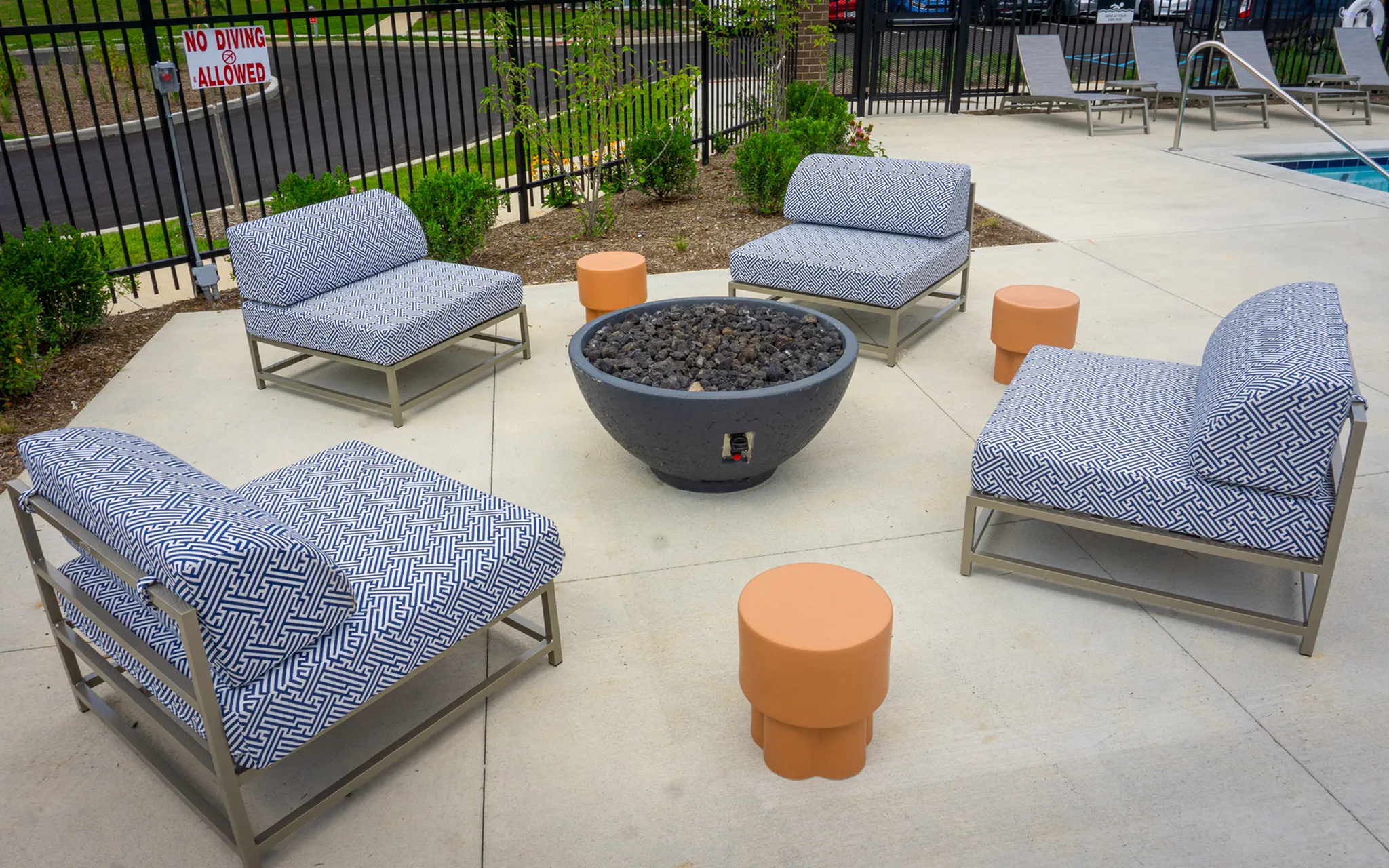 Chic outdoor seating area with patterned lounge chairs surrounding a modern fire pit, offering a perfect space for relaxation and social gatherings.