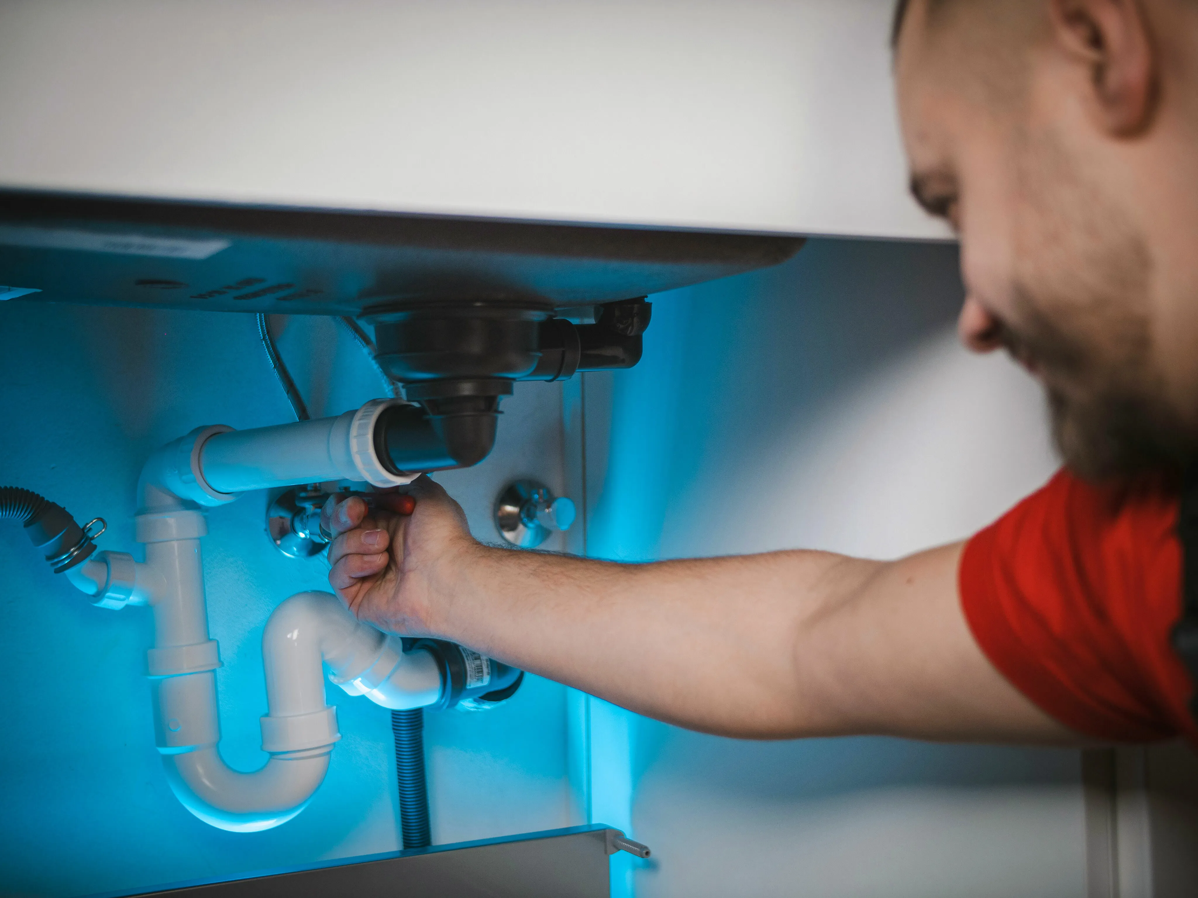 Professional plumber confidently working on modern under-sink piping system with focused precision and efficiency.