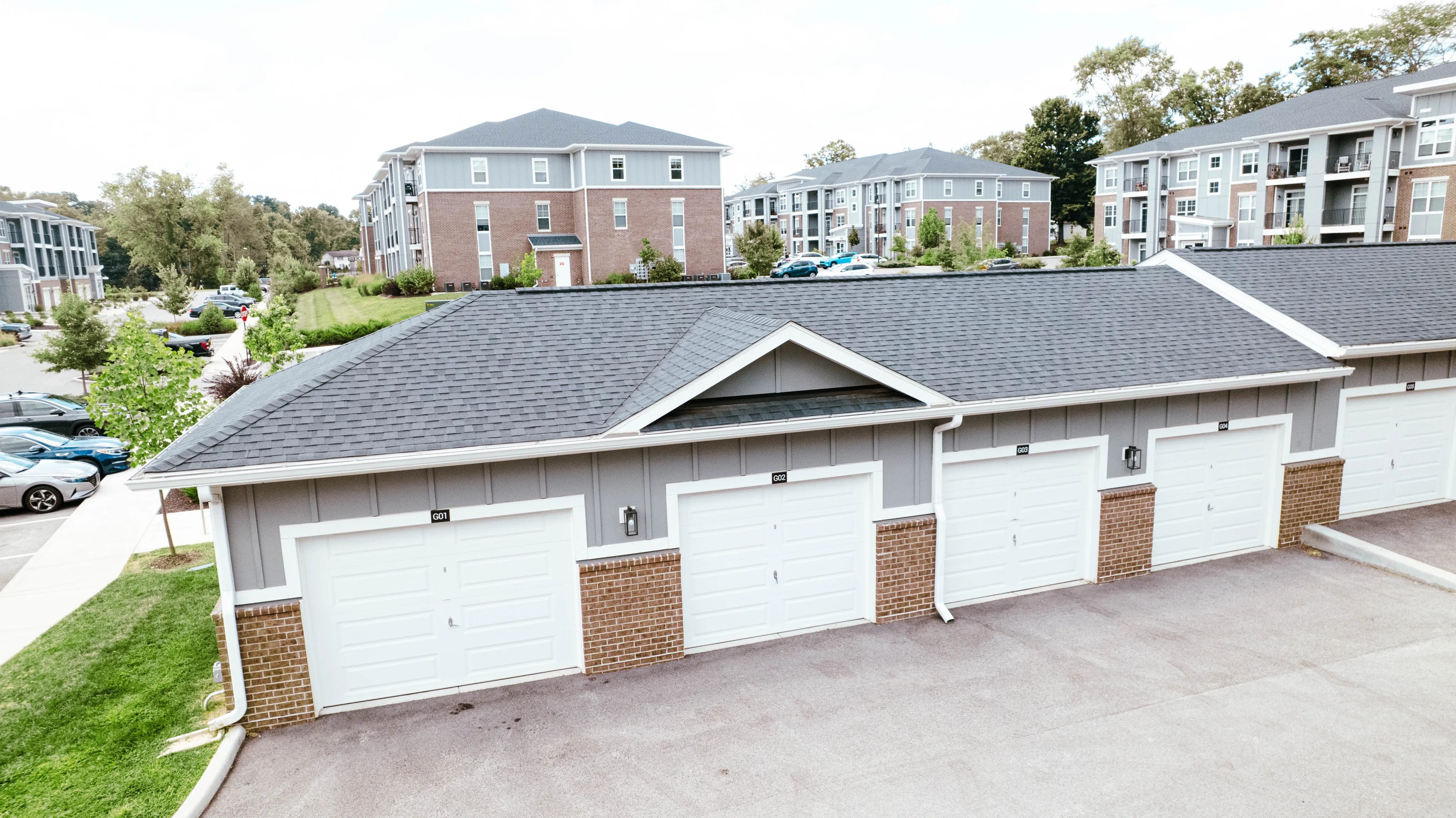 Inviting residential complex showcasing modern garages, lush green surroundings, and contemporary multi-story apartment buildings.