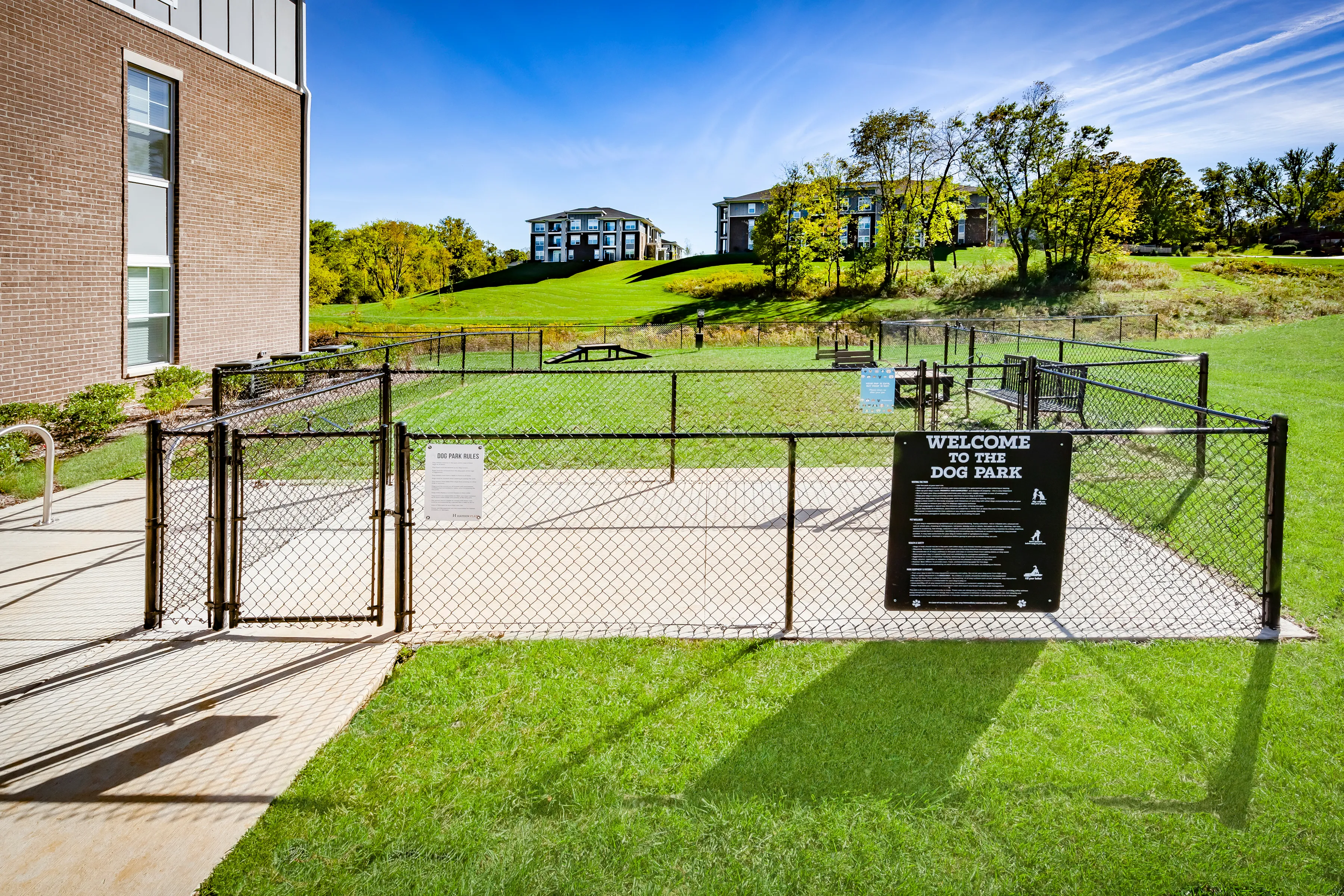 Inviting fenced dog park with lush green surroundings, perfect for pet-friendly apartment living.