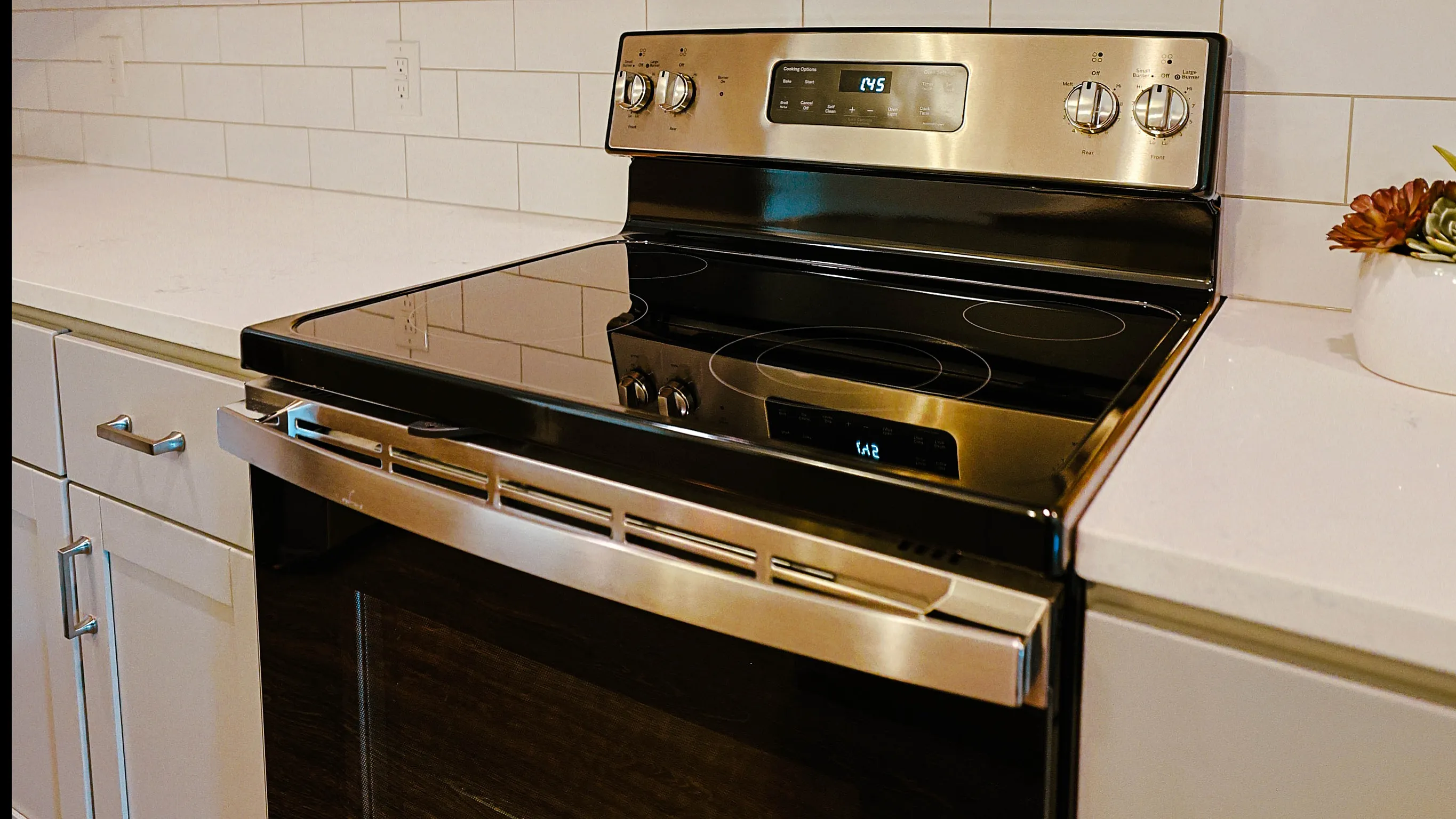 Modern kitchen with sleek stainless steel appliances, including a microwave and stove, complemented by elegant white cabinetry and subway tile backsplash.