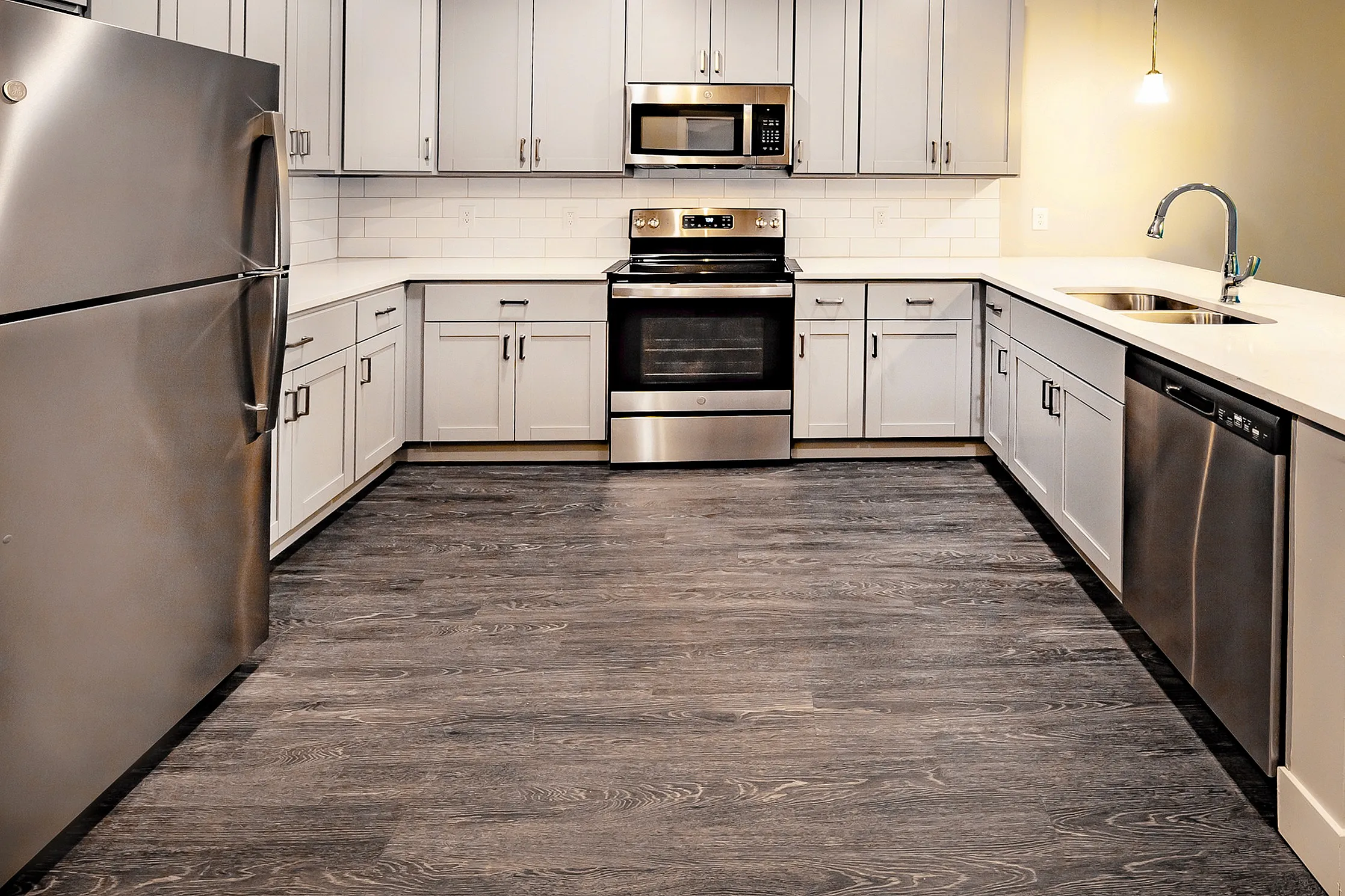 Modern kitchen with sleek stainless steel appliances, elegant white cabinets, and stylish pendant lighting.