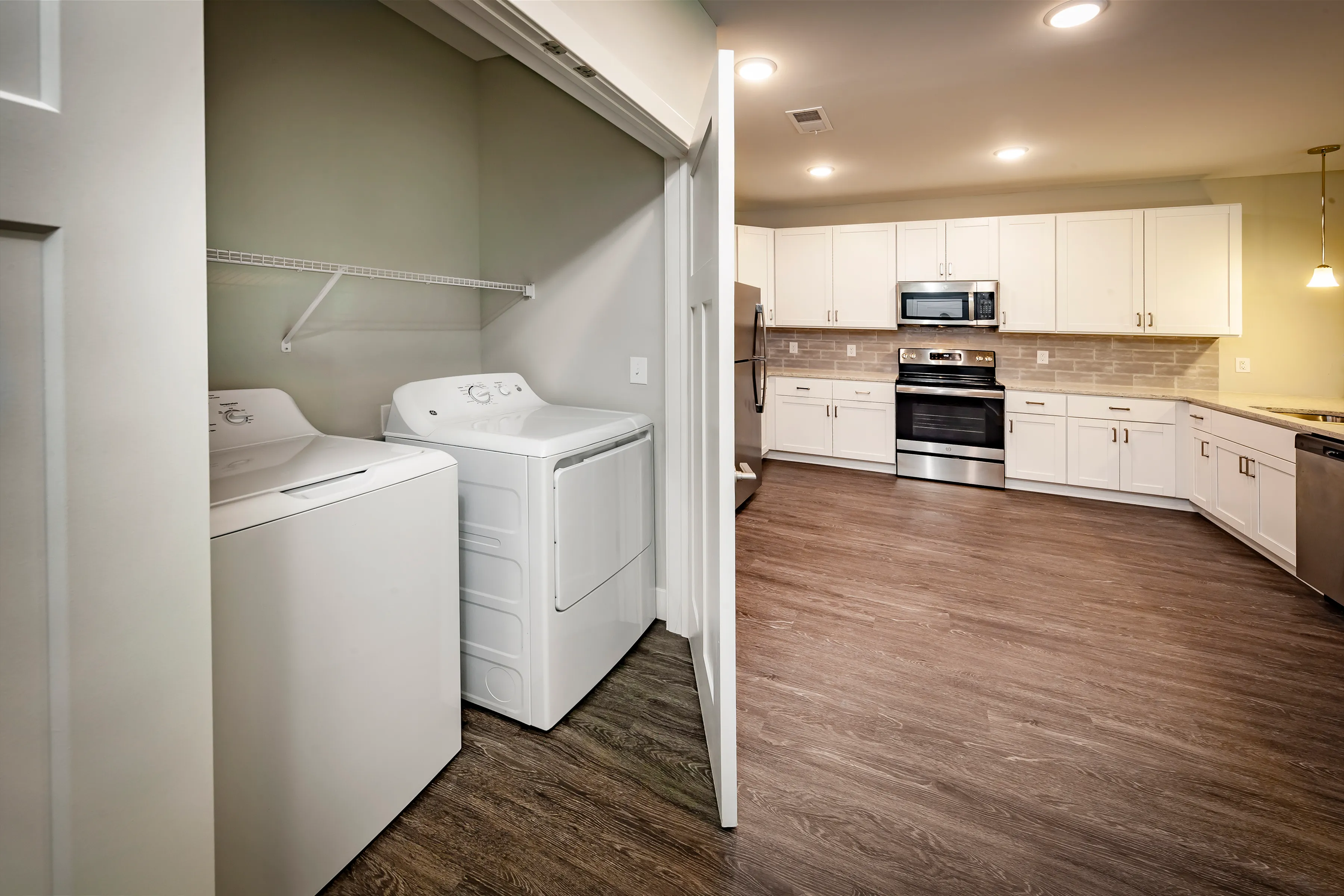 Modern kitchen and laundry area featuring sleek stainless steel appliances, ample cabinetry, and in-unit washer and dryer for convenience.