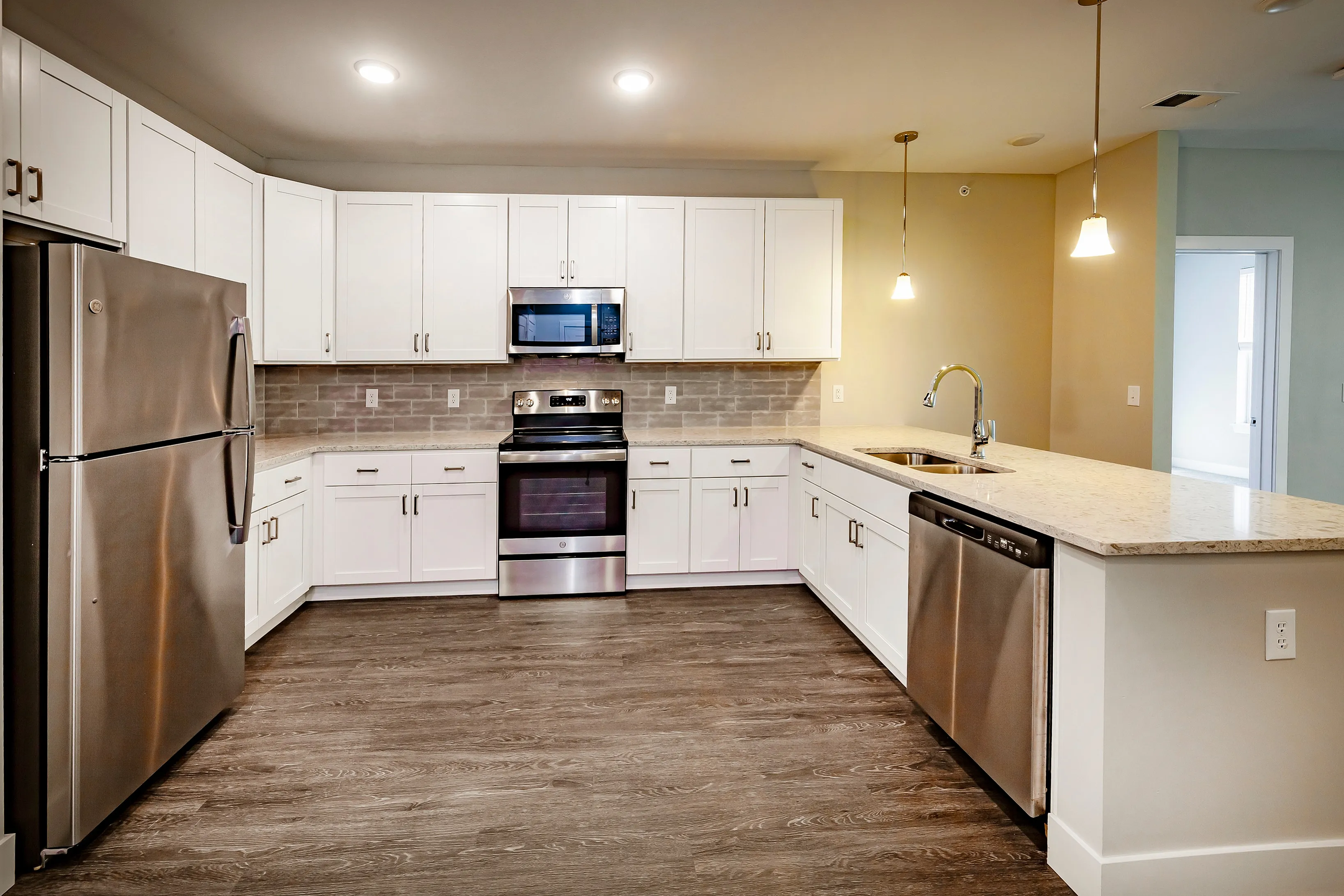Modern kitchen with sleek stainless steel appliances, stylish white cabinetry, and elegant pendant lighting.